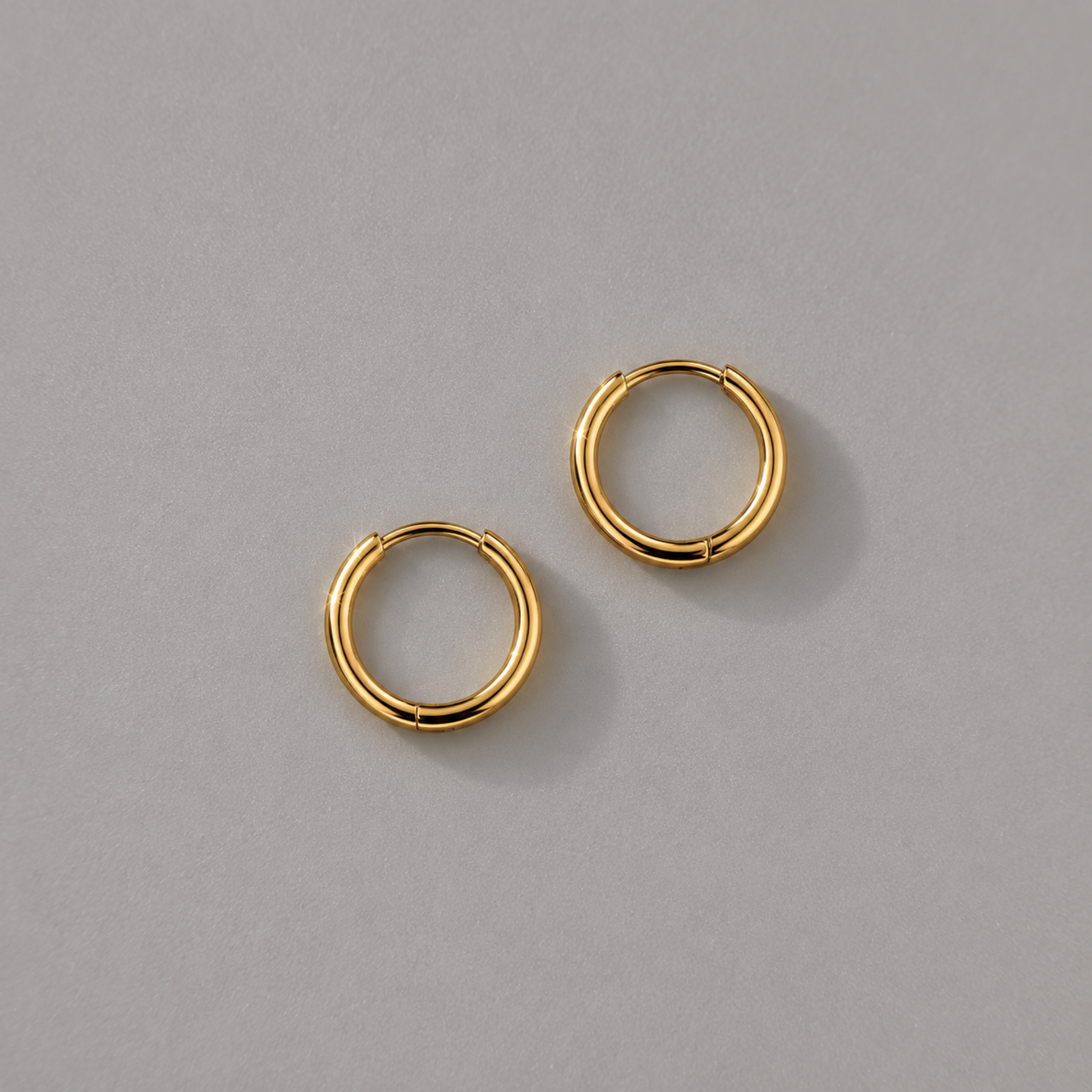 Pair of dainty thin gold hoop earrings on a gray background