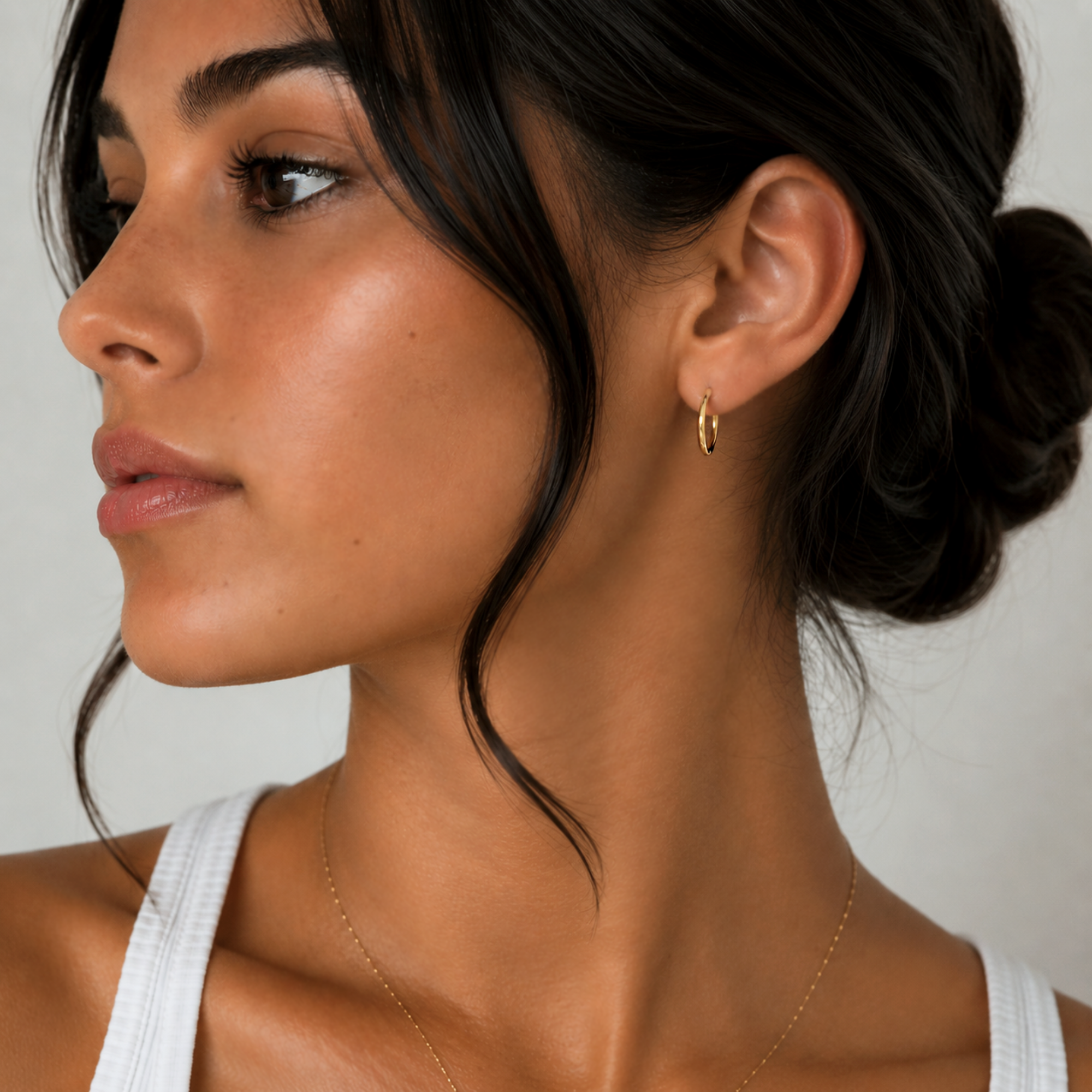 dainty gold huggie hoop earrings on model