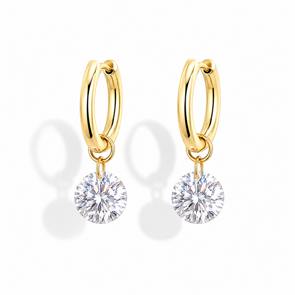 A pair of gold huggie hoop earrings with round-cut clear gemstones dangling from the hoops, shown on a clean white background with soft shadows.
