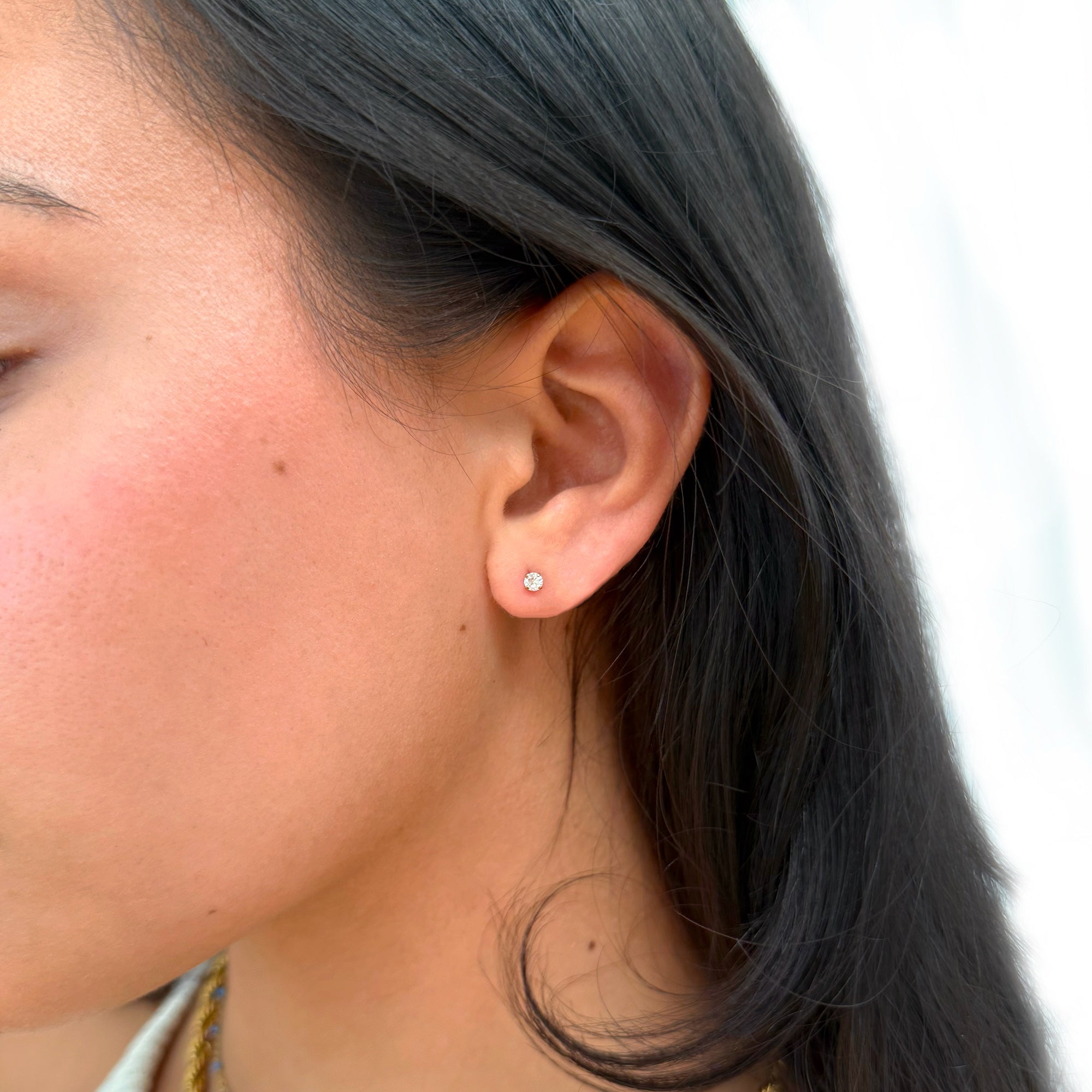 Close-up of an ear wearing a diamond earring with a blurred background