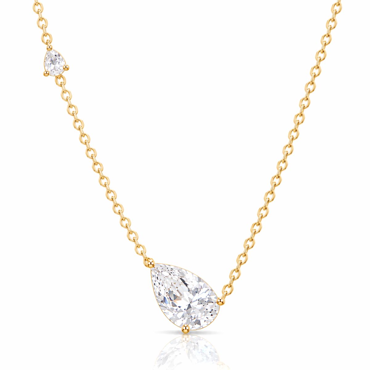 A delicate yellow gold chain necklace featuring a pear-cut clear gemstone pendant and a smaller matching gemstone accent on the chain, set against a clean white background with a subtle reflection.