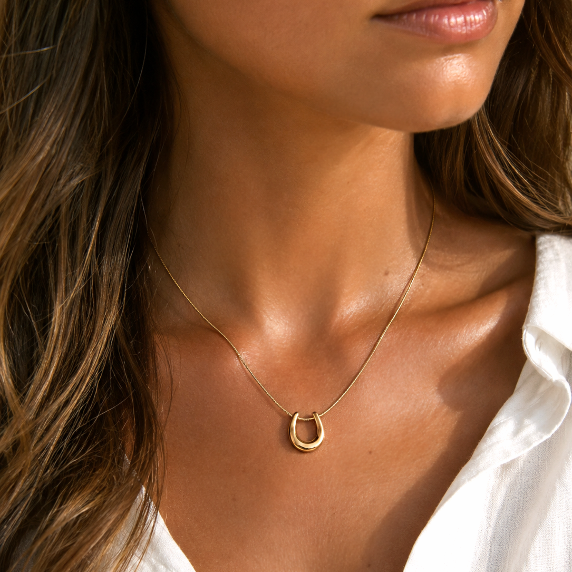 model wearing gold horseshoe pendant necklace