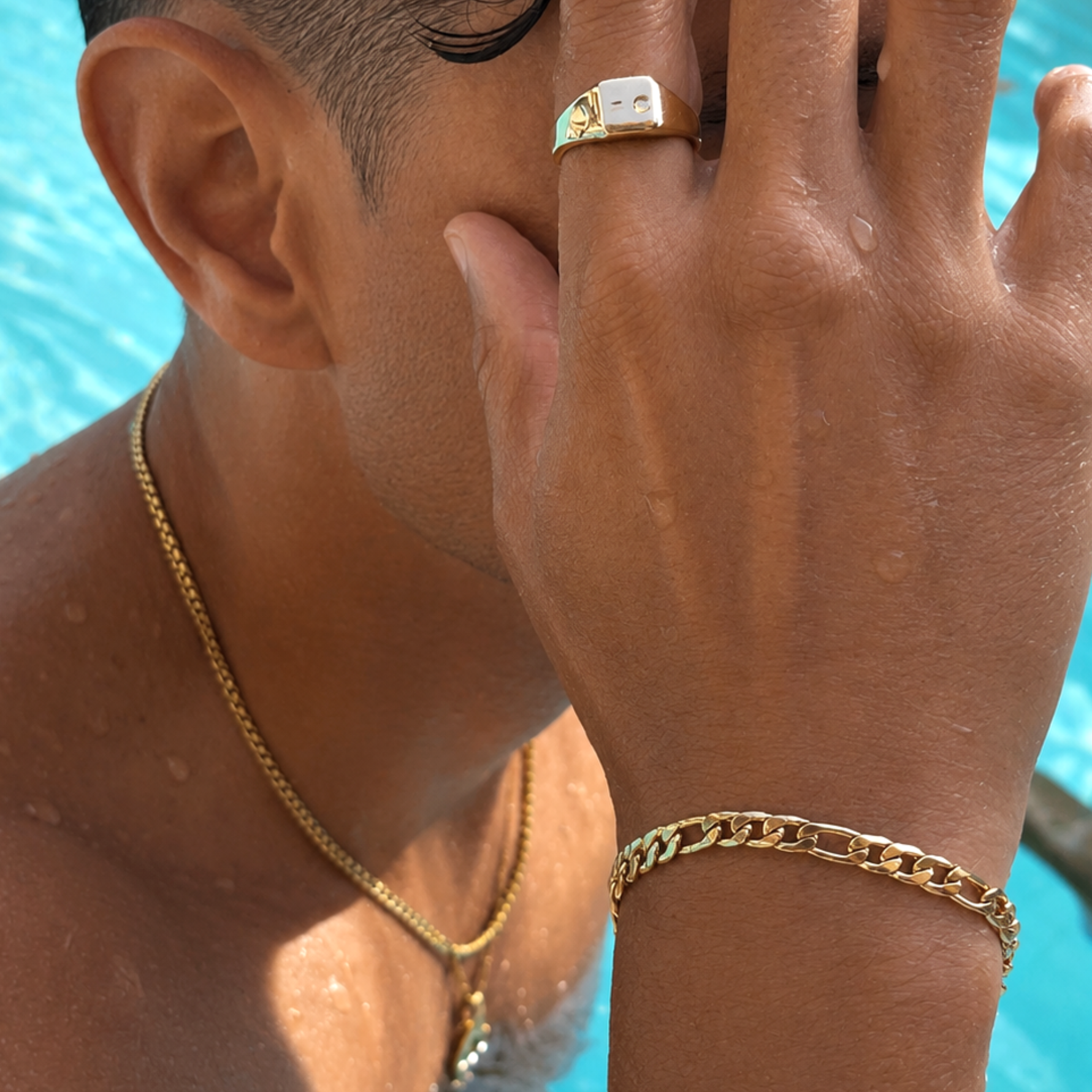 Man wearing waterproof gold signet ring and Cuban chain bracelet in a pool