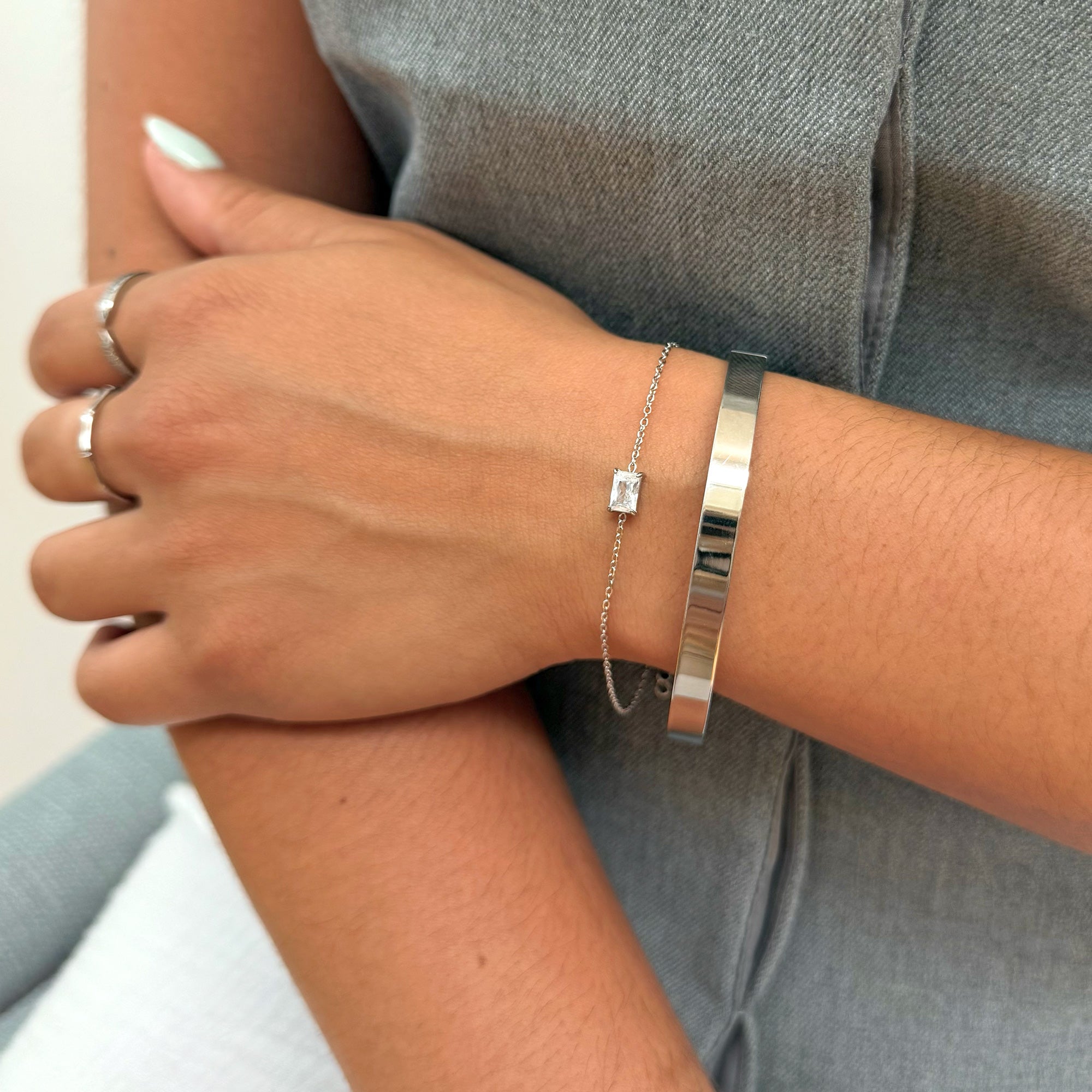 Close-up of a person's wrist wearing silver marquis stone bracelets and silver cuff