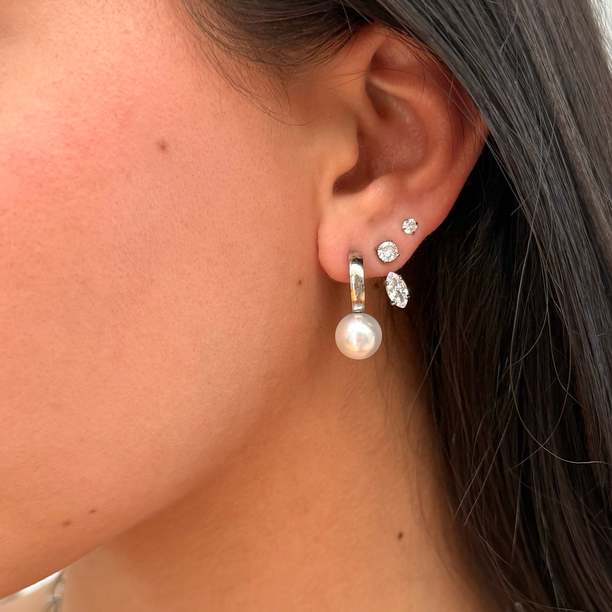 Close-up of an ear wearing pearl and crystal earrings.