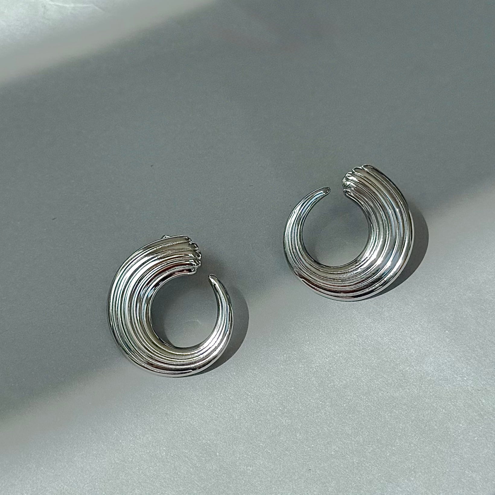 silver vintage ribbed curve earrings on grey background