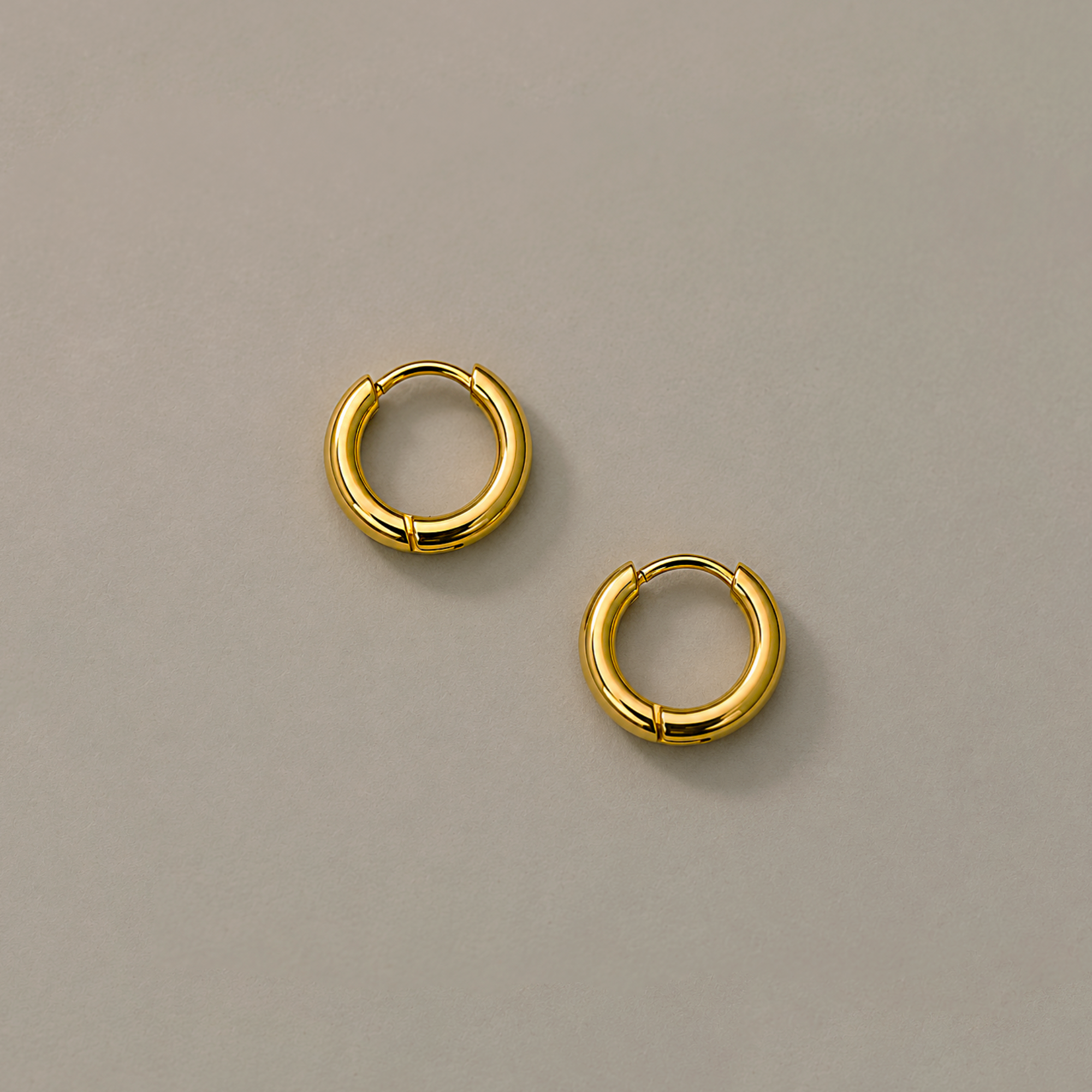 Pair of 8mm gold hoop earrings on a beige background
