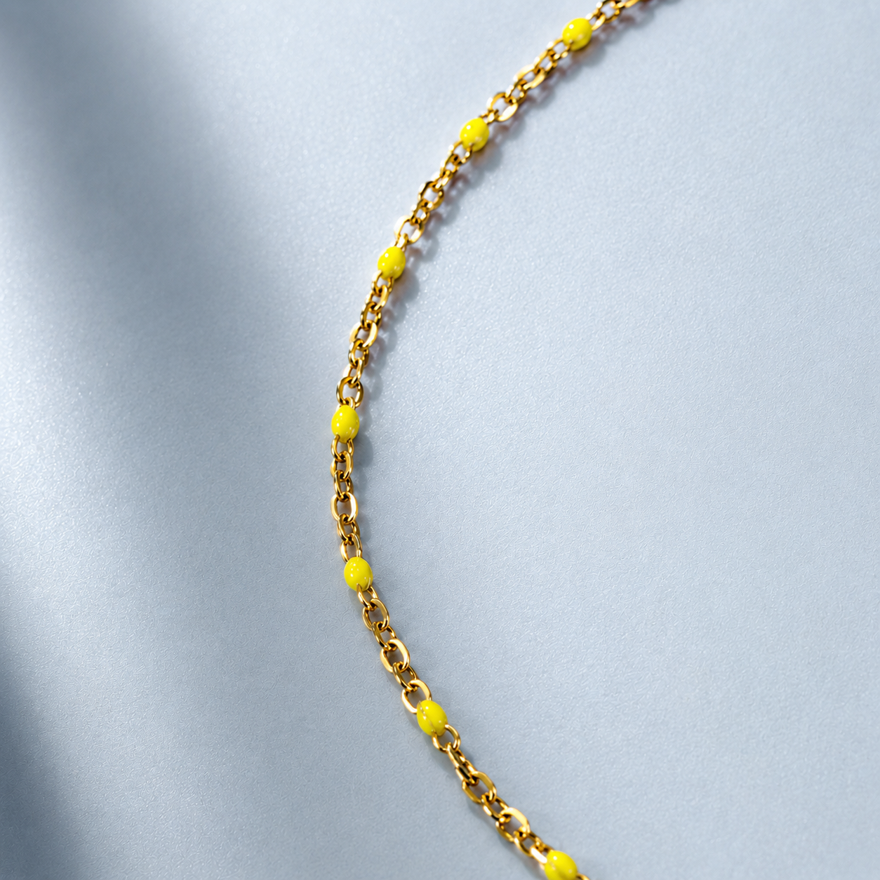 Gold neon yellow beaded chain anklet on a light gray background