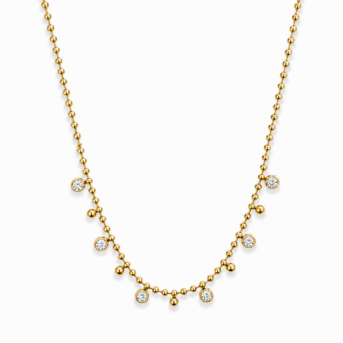 A delicate yellow gold necklace featuring a beaded chain with seven small, round bezel-set clear gemstones arranged in a gentle arc, displayed on a clean white background.