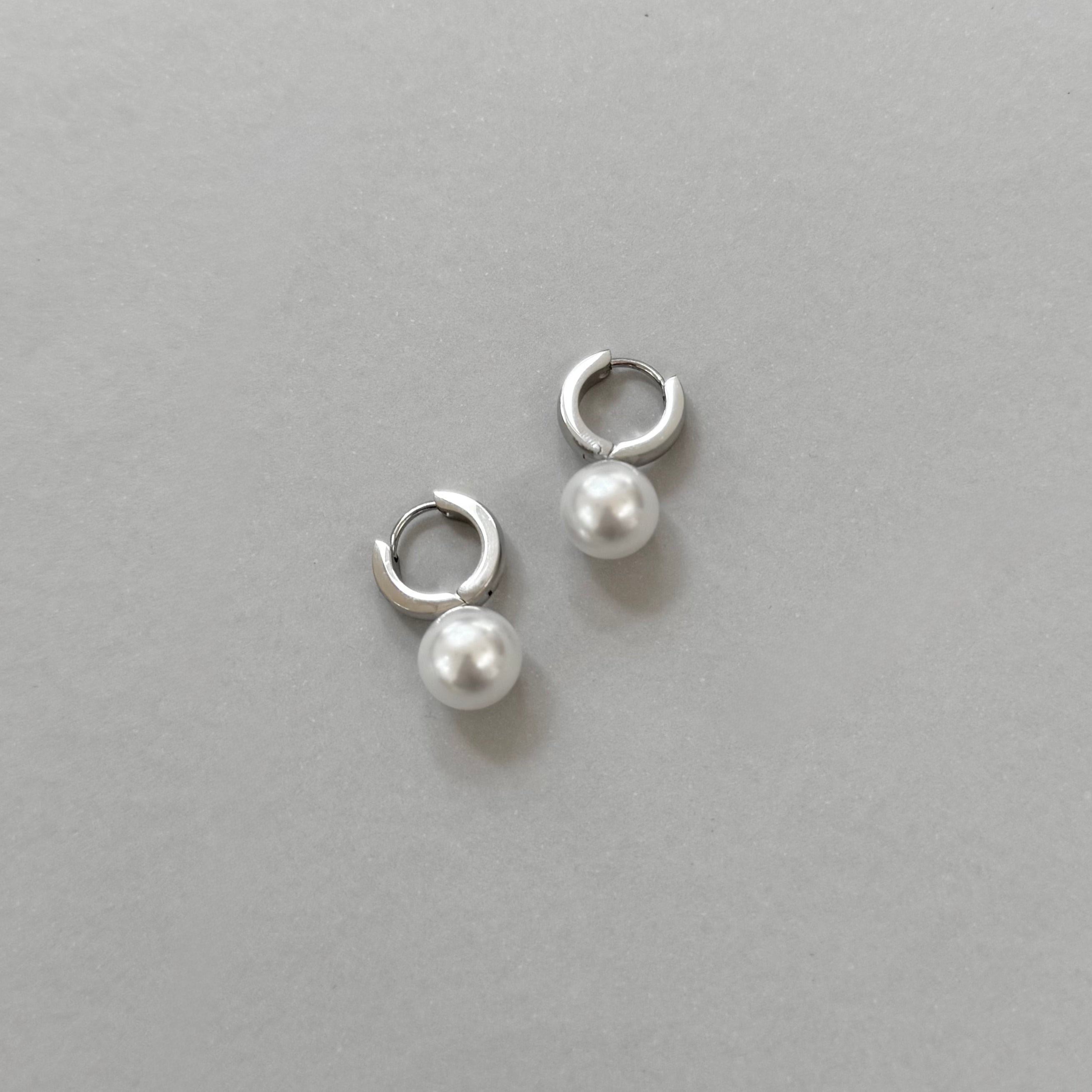 Pair of silver hoop earrings with pearl drops on a gray background