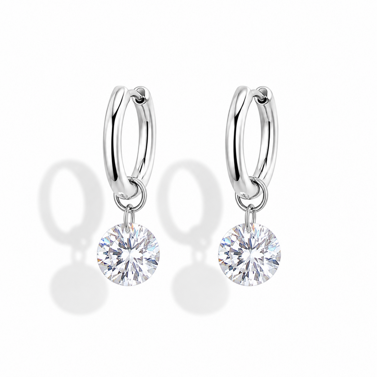 A pair of silver hoop earrings with round clear gemstones dangling from the hoops, shown on a clean white background with soft shadows.
