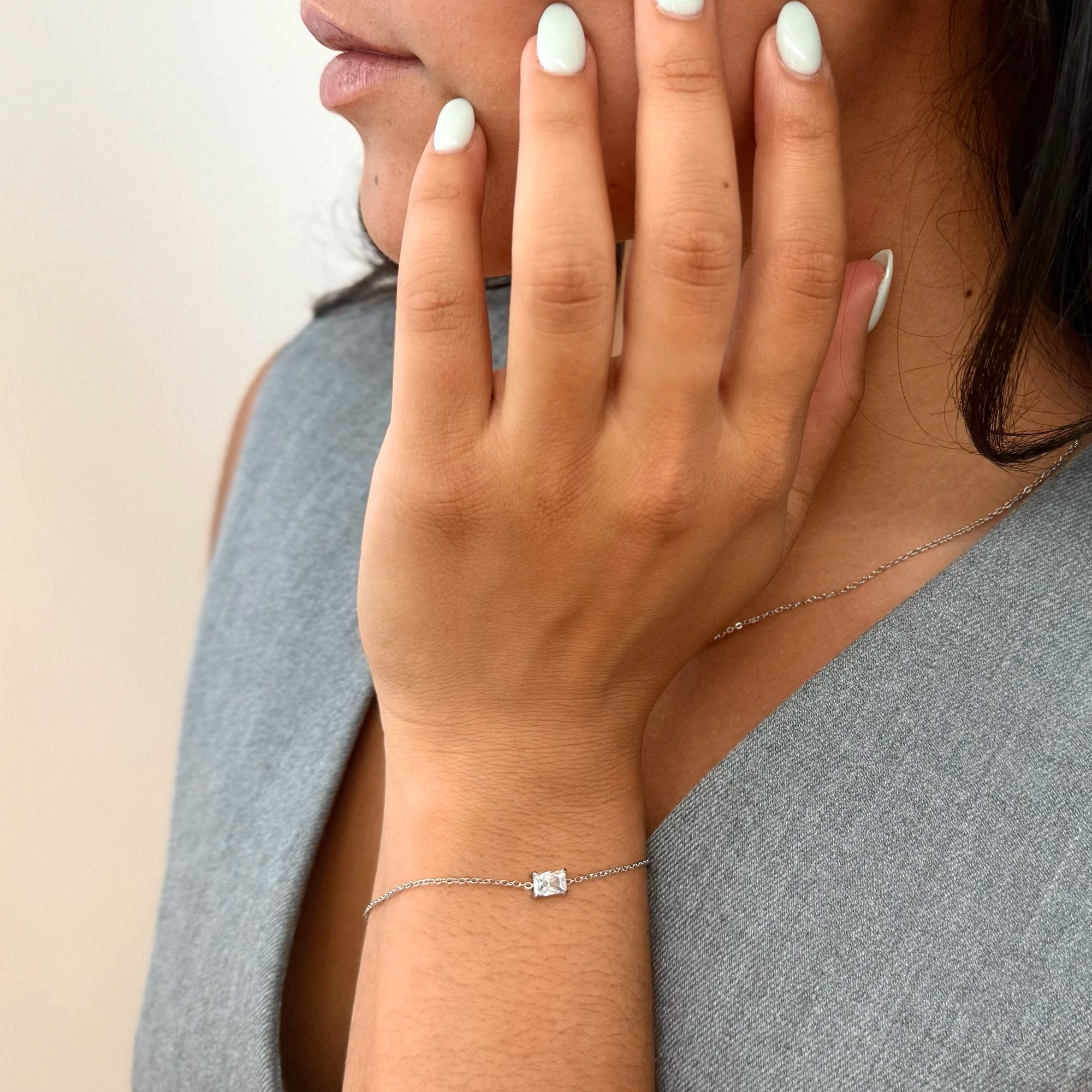 Close-up of a hand wearing a silver marquis stone  bracelet with a diamond clasp.