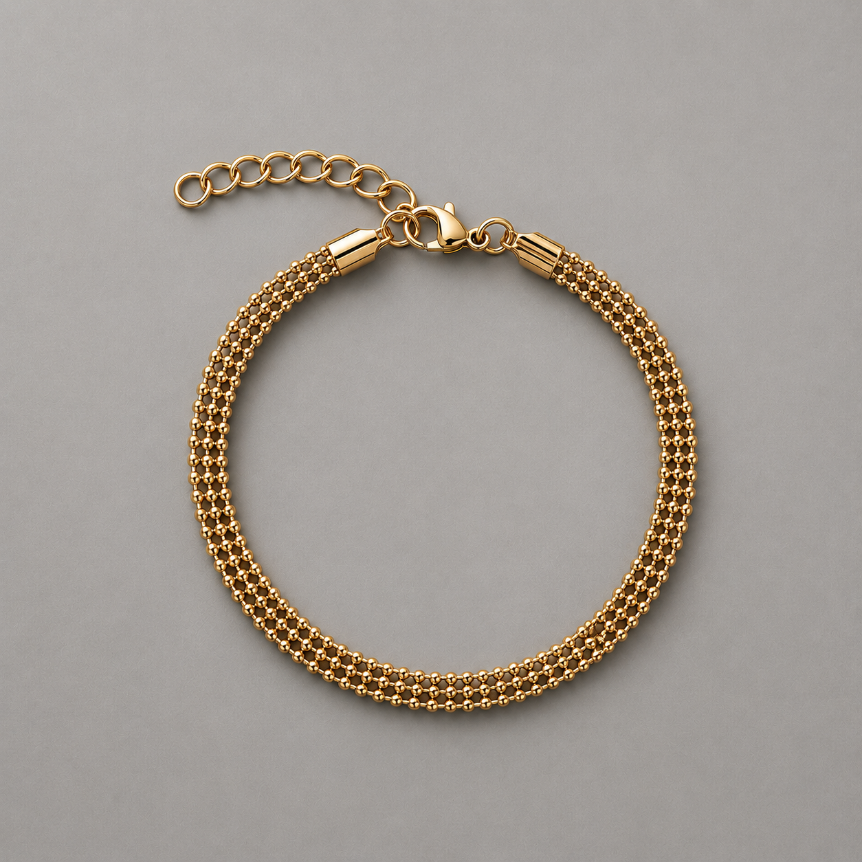 Gold beaded chain bracelet on a gray background