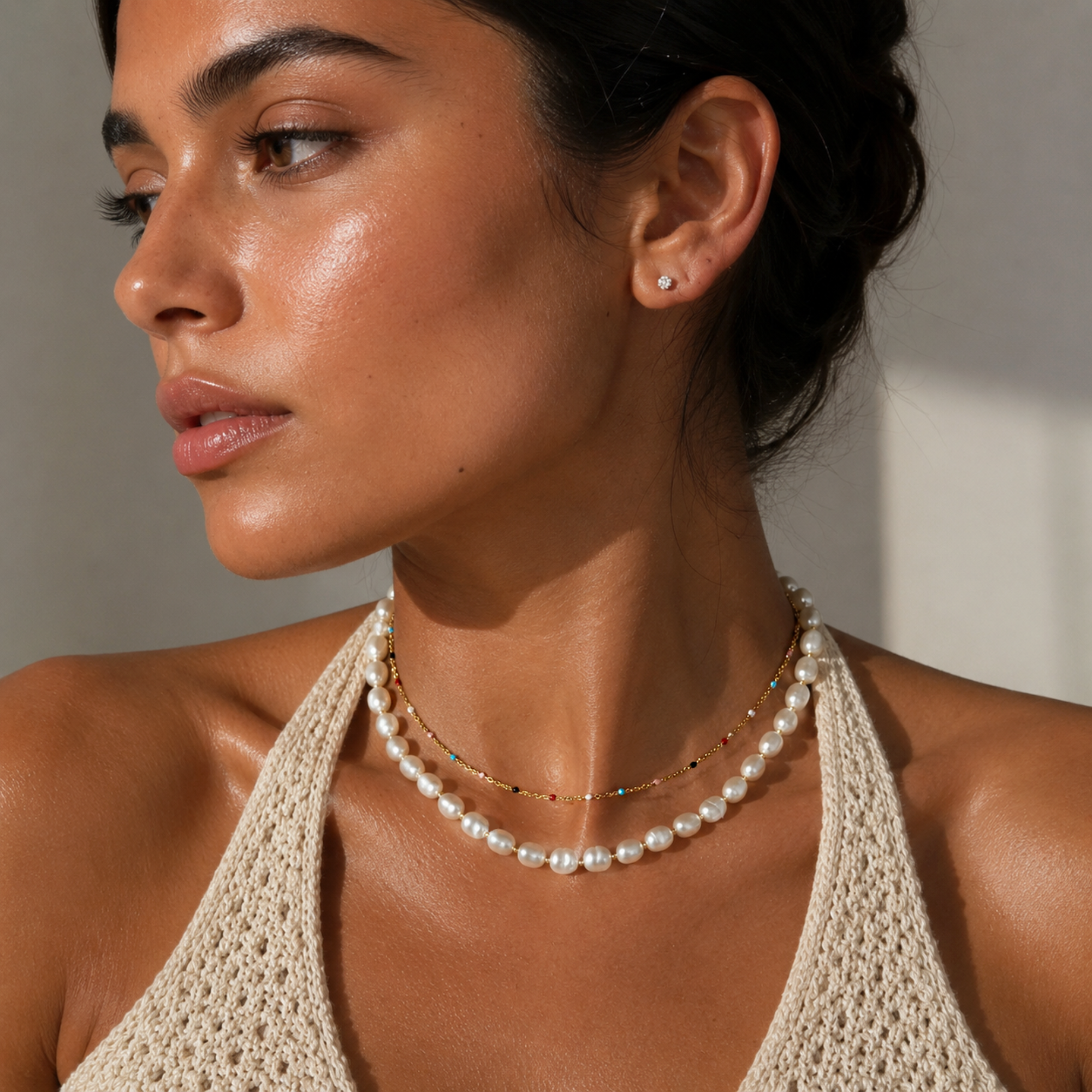 model wearing adjustable dainty gold rainbow beaded chain necklace high stacked with pearl necklace below