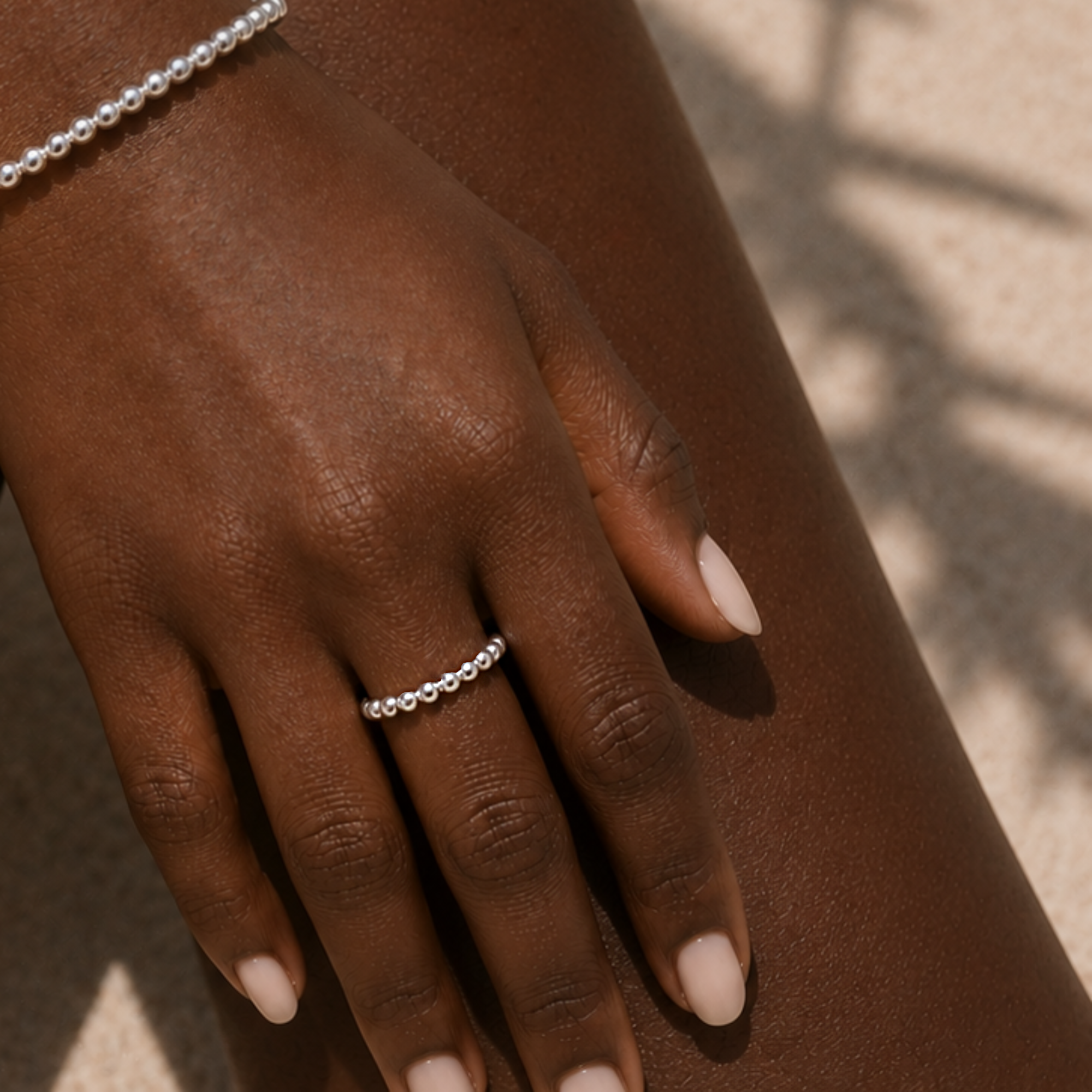 Close-up of a hand wearing a silver ring on a neutral background
