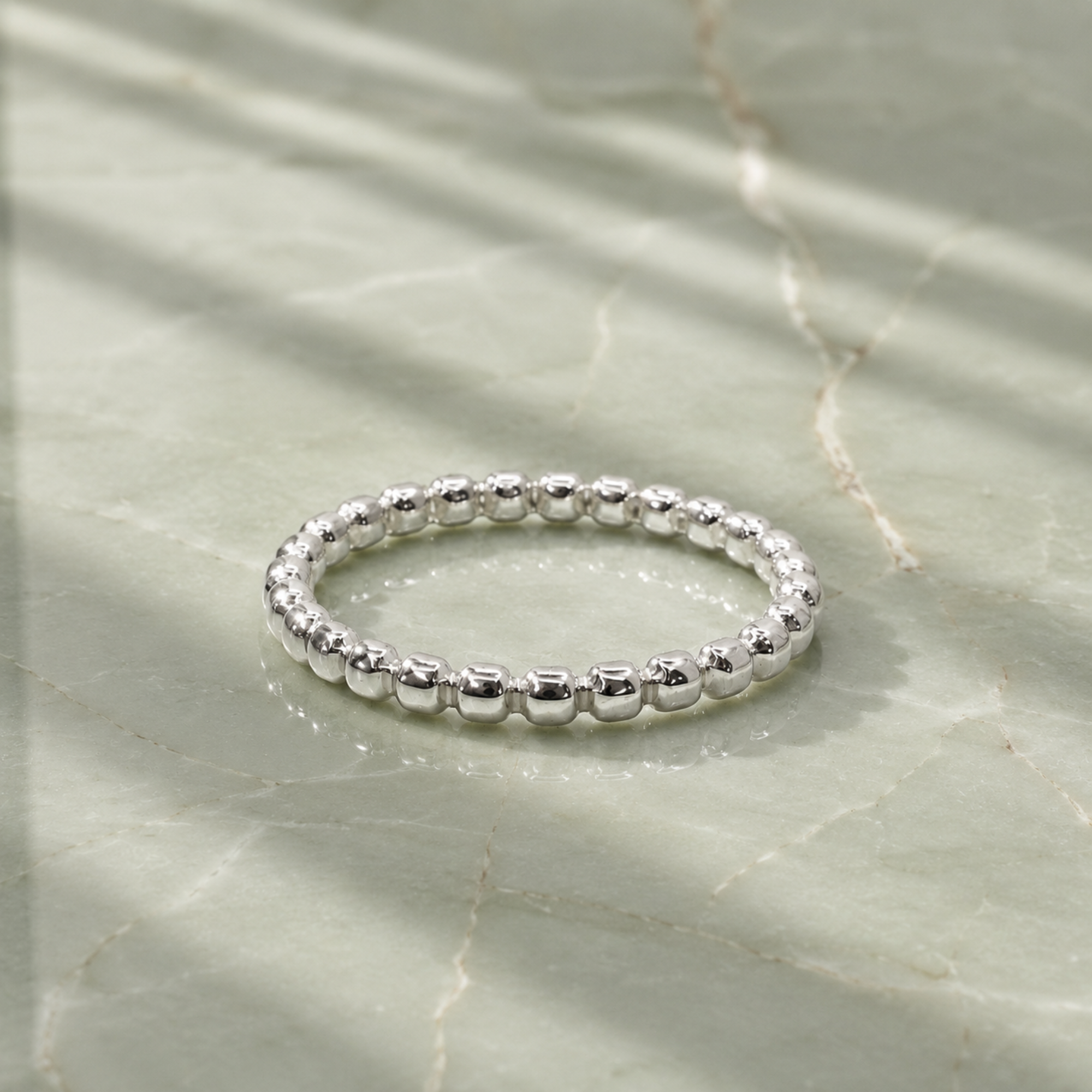 Dainty silver beaded ring on a light marble surface