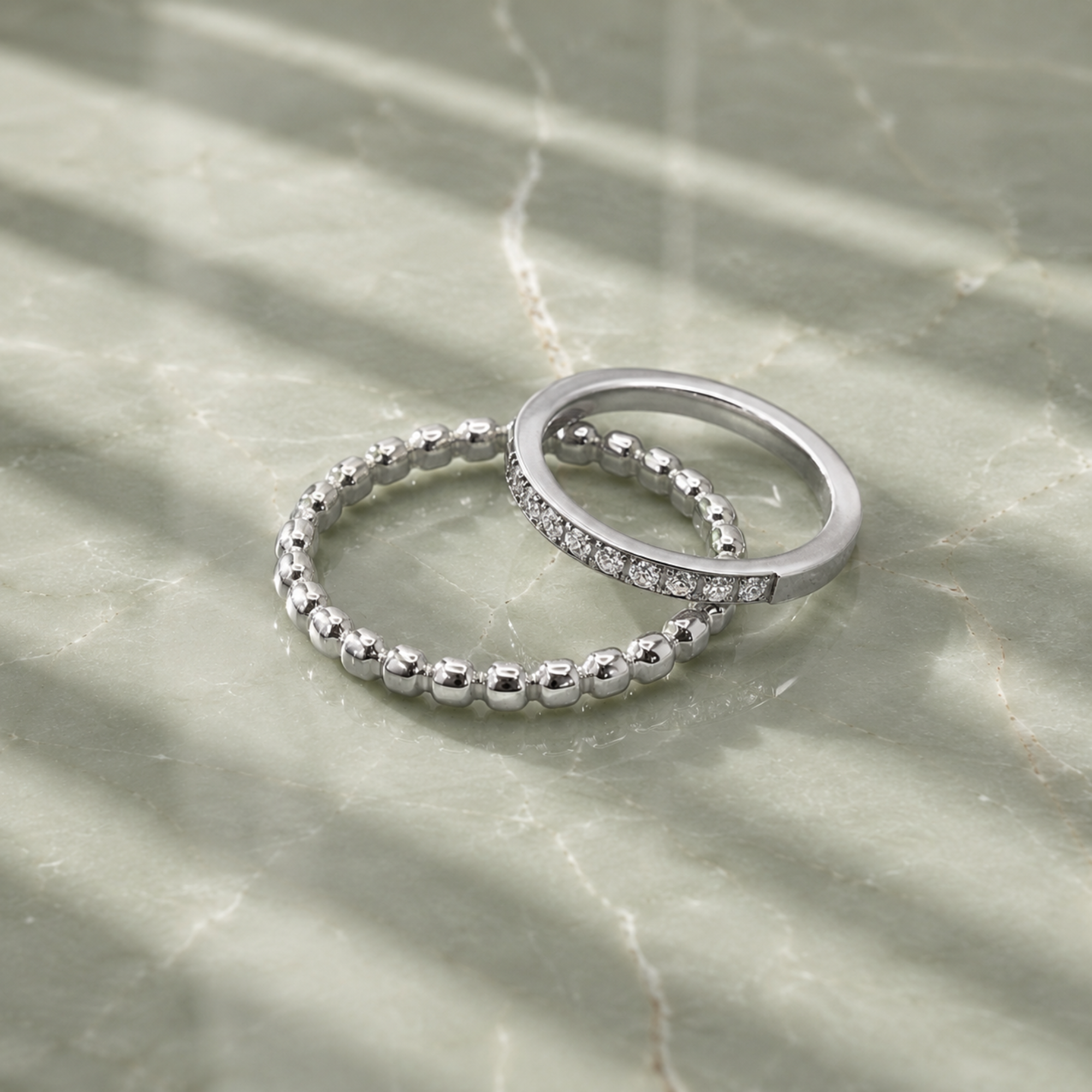 Two silver rings on a marble surface