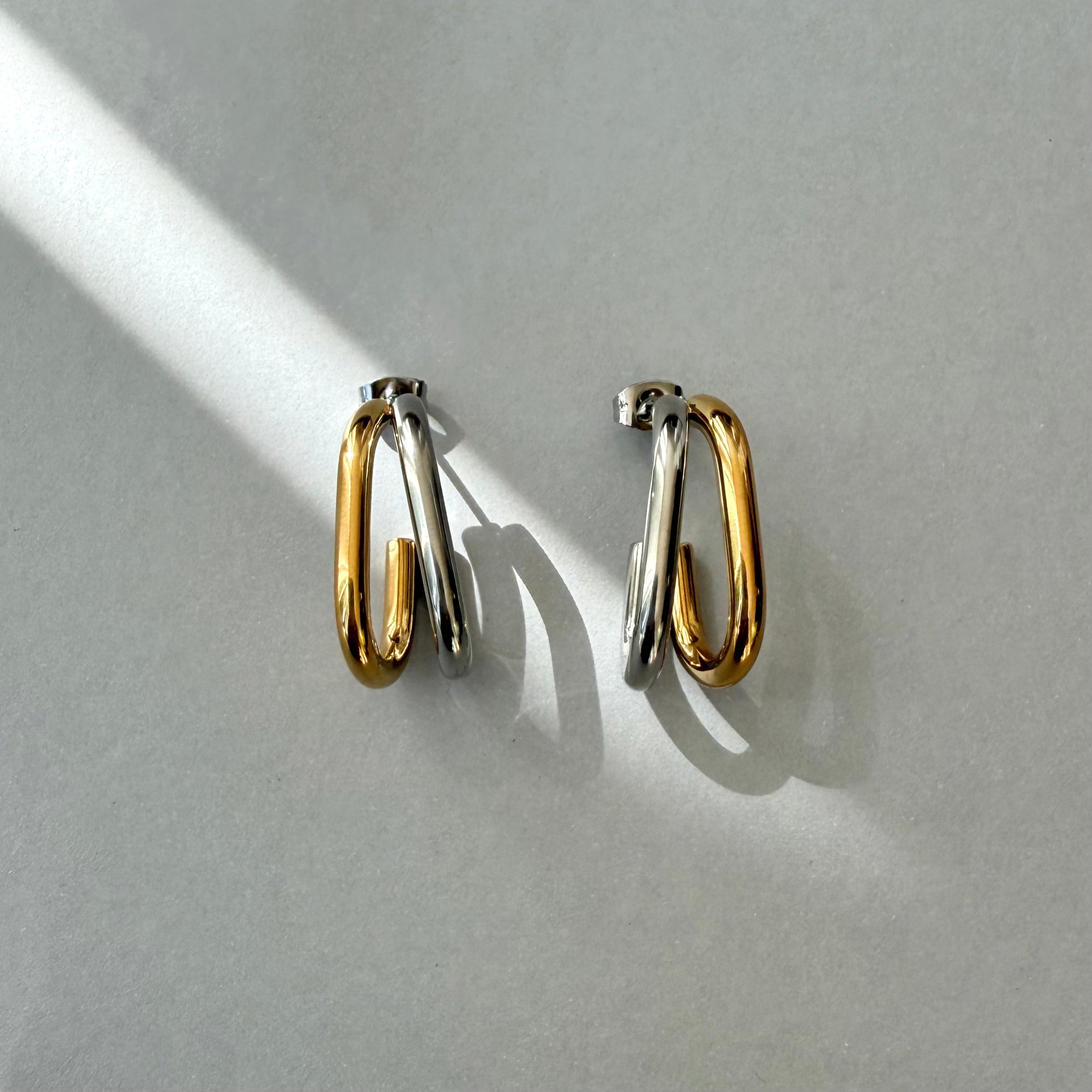 Pair of modern dual tone hoop earrings on a light gray background