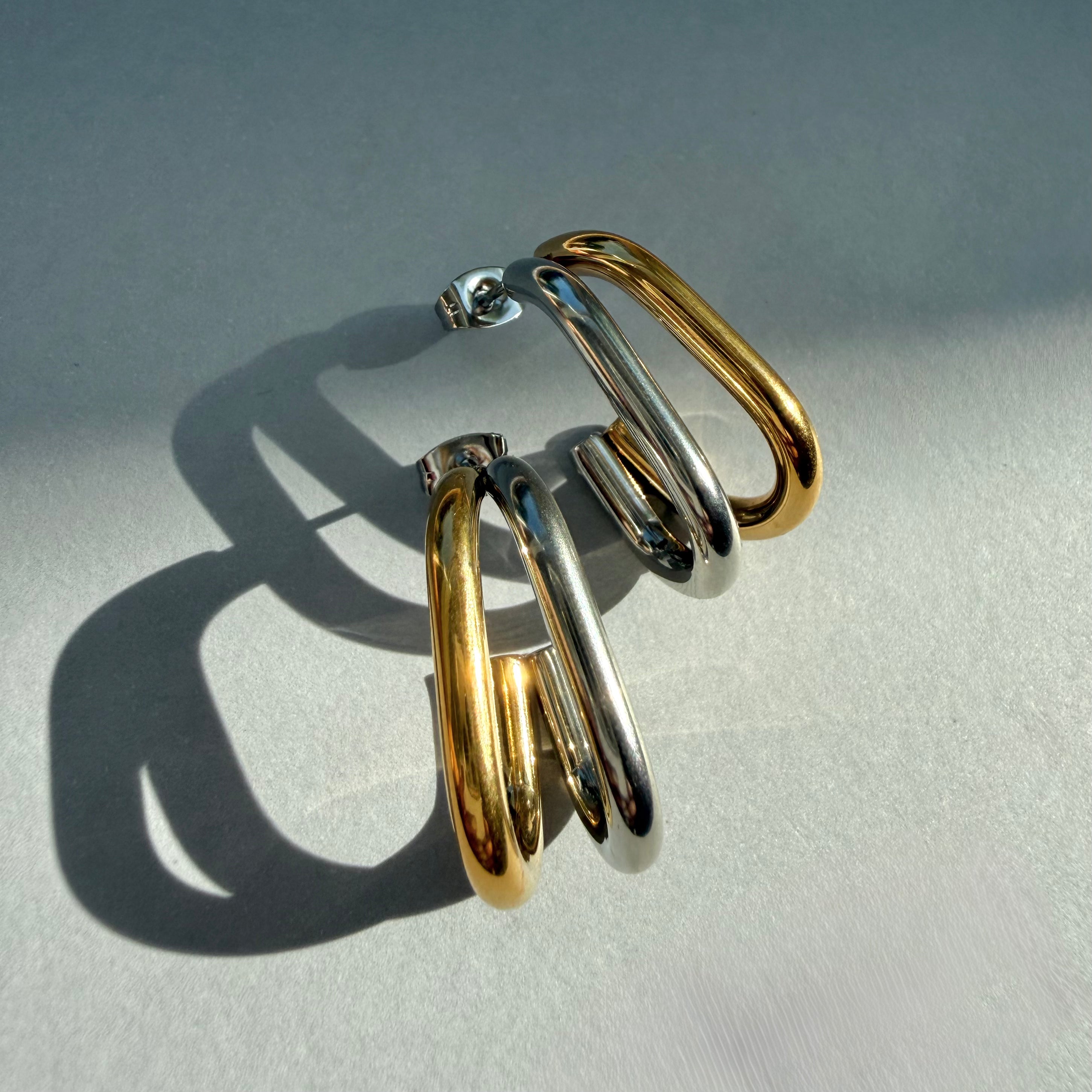 Pair of dual tone oval hoop earrings on a light gray background
