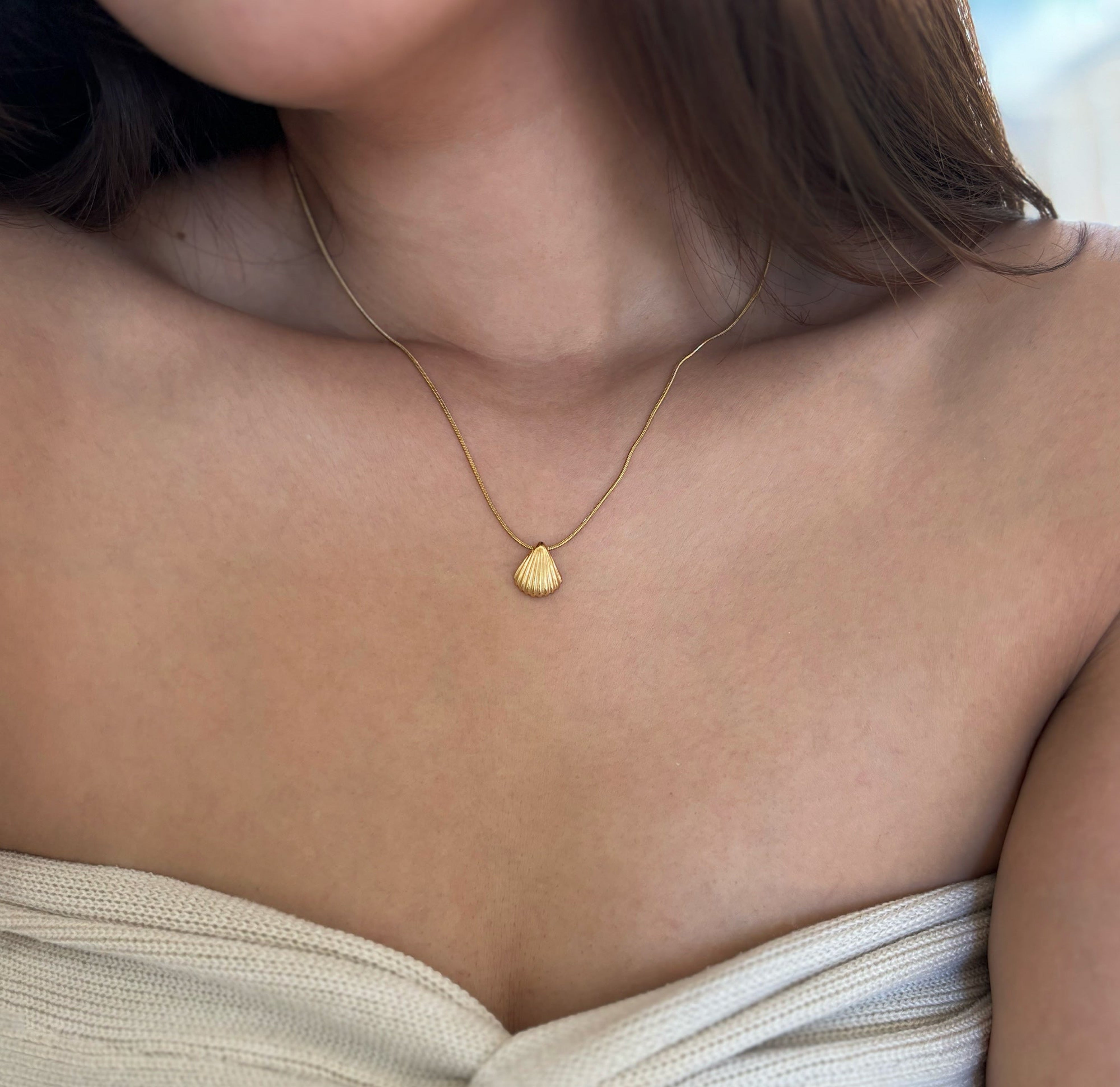 gold sea shell pendant necklace worn on model