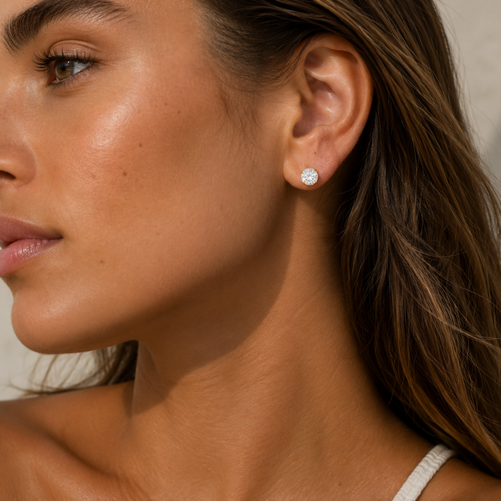 Close-up of a woman wearing diamond earrings with a neutral background