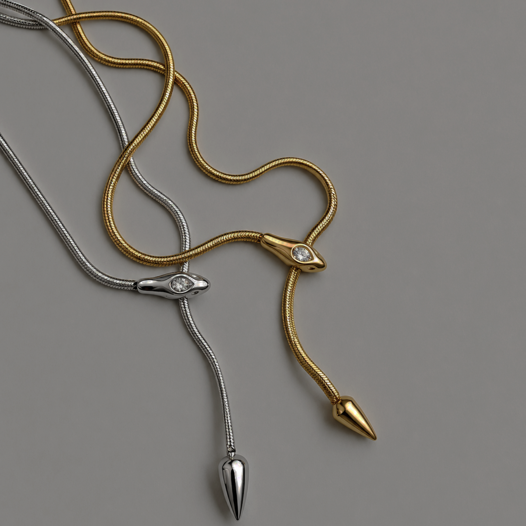 Gold and silver serpentine snake necklaces on a gray background
