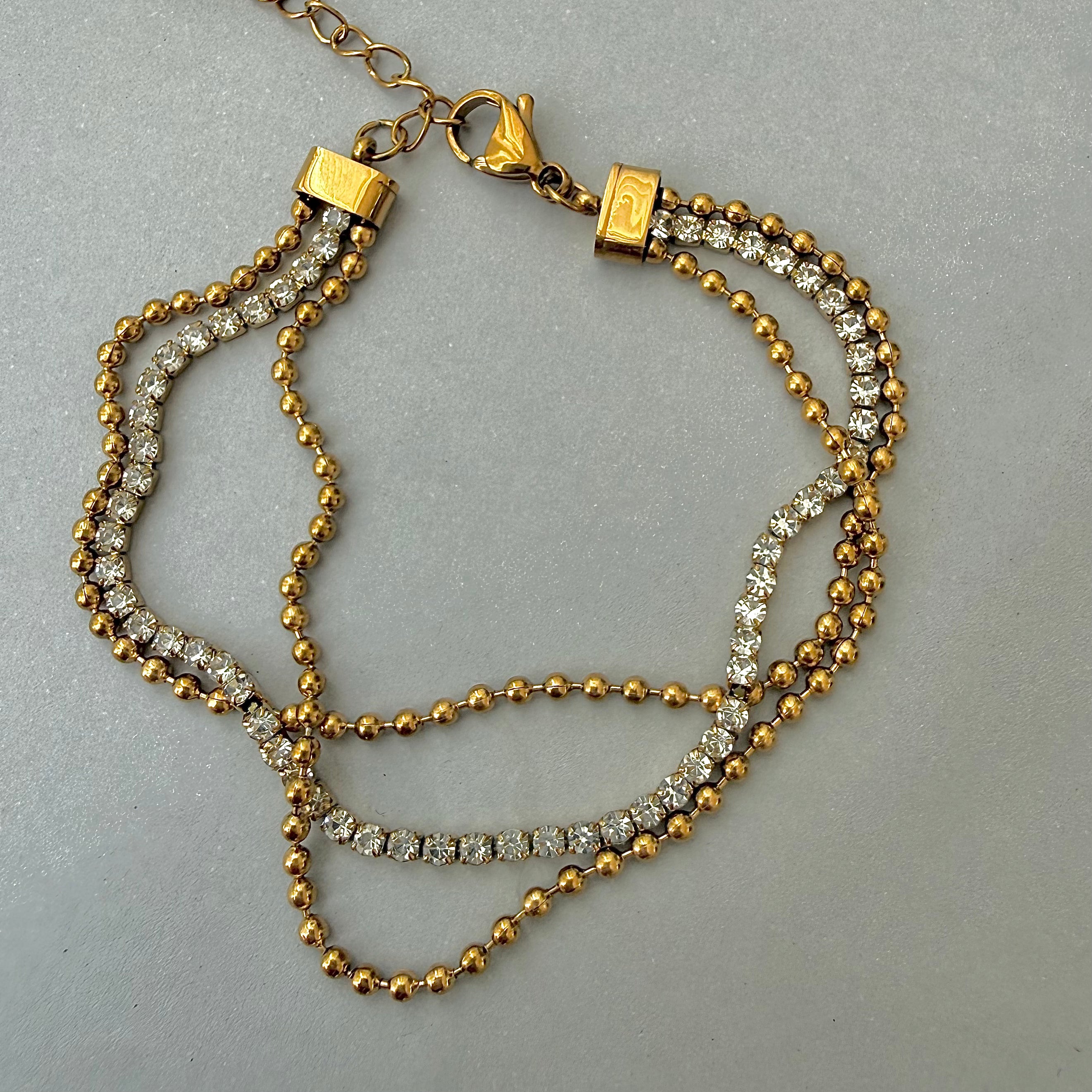 gold beaded tennis bracelet on grey background