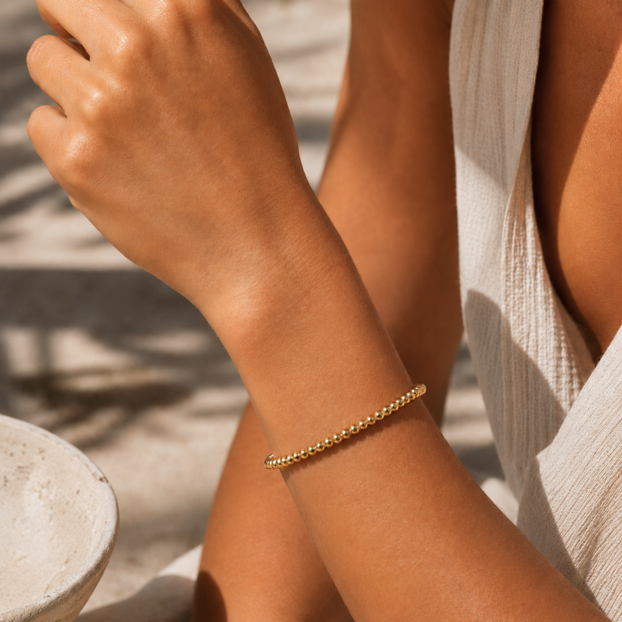Gold bracelet on a person's wrist with a neutral background