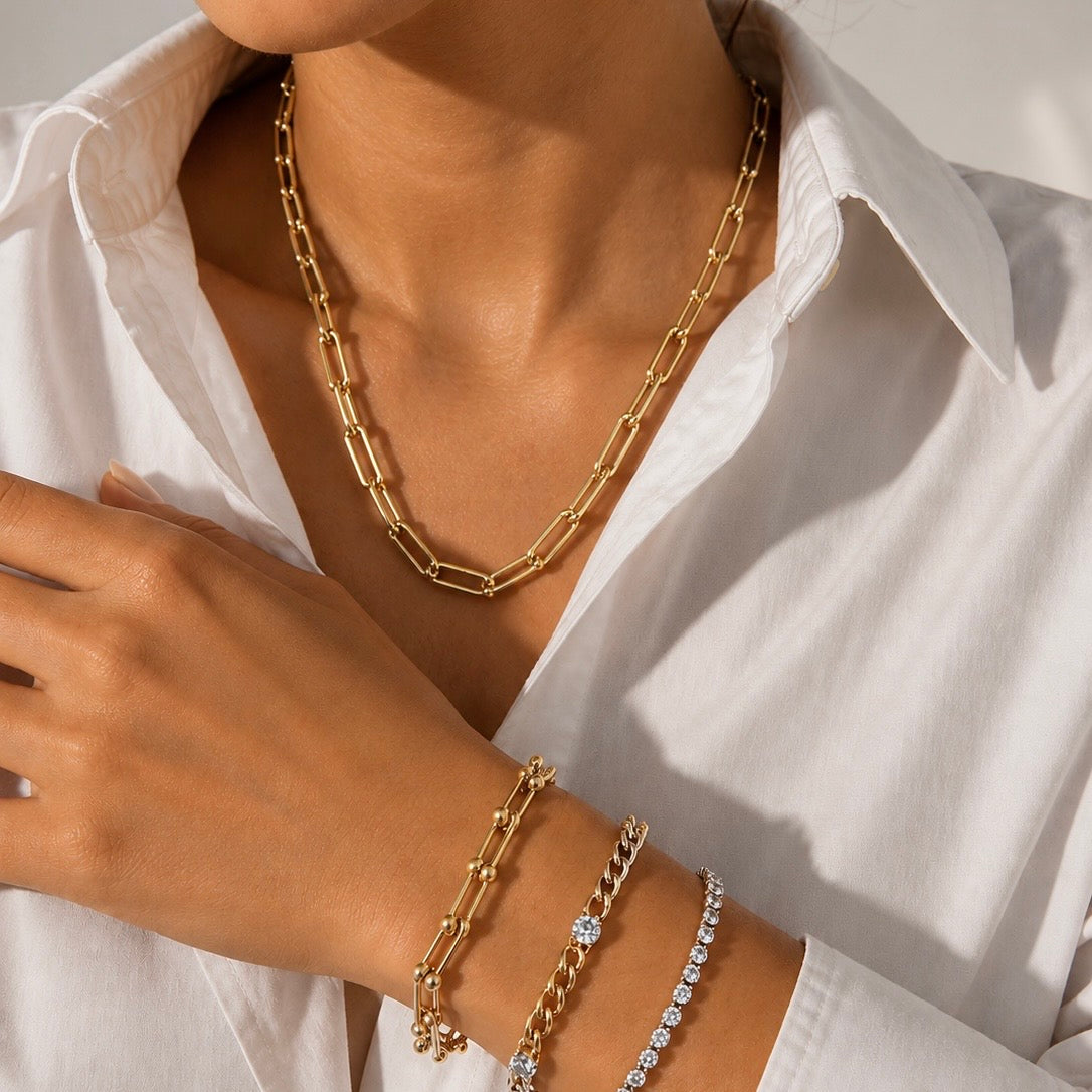 Gold hardware chain necklace and bracelet on a person wearing a white shirt.