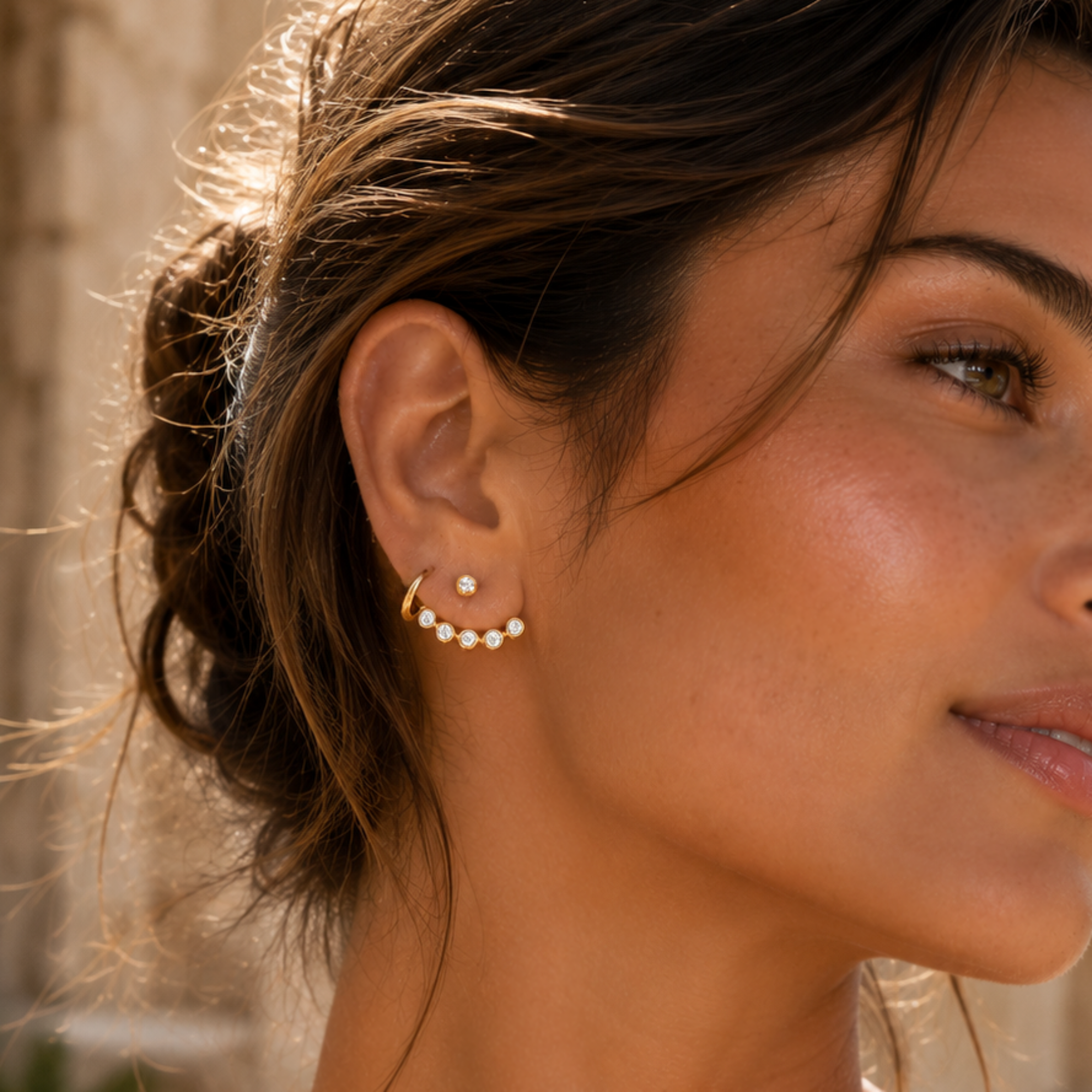 Close-up of a woman wearing a gold ear jacket earring with white stones
