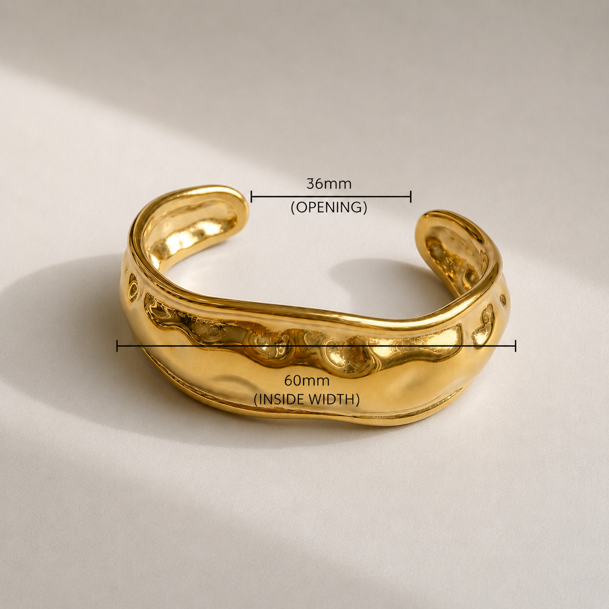 Gold bangle with measurements on a beige background