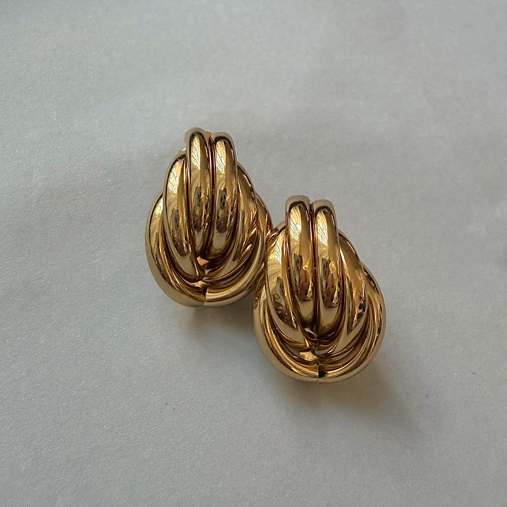 Pair of gold knot earrings on a light gray background