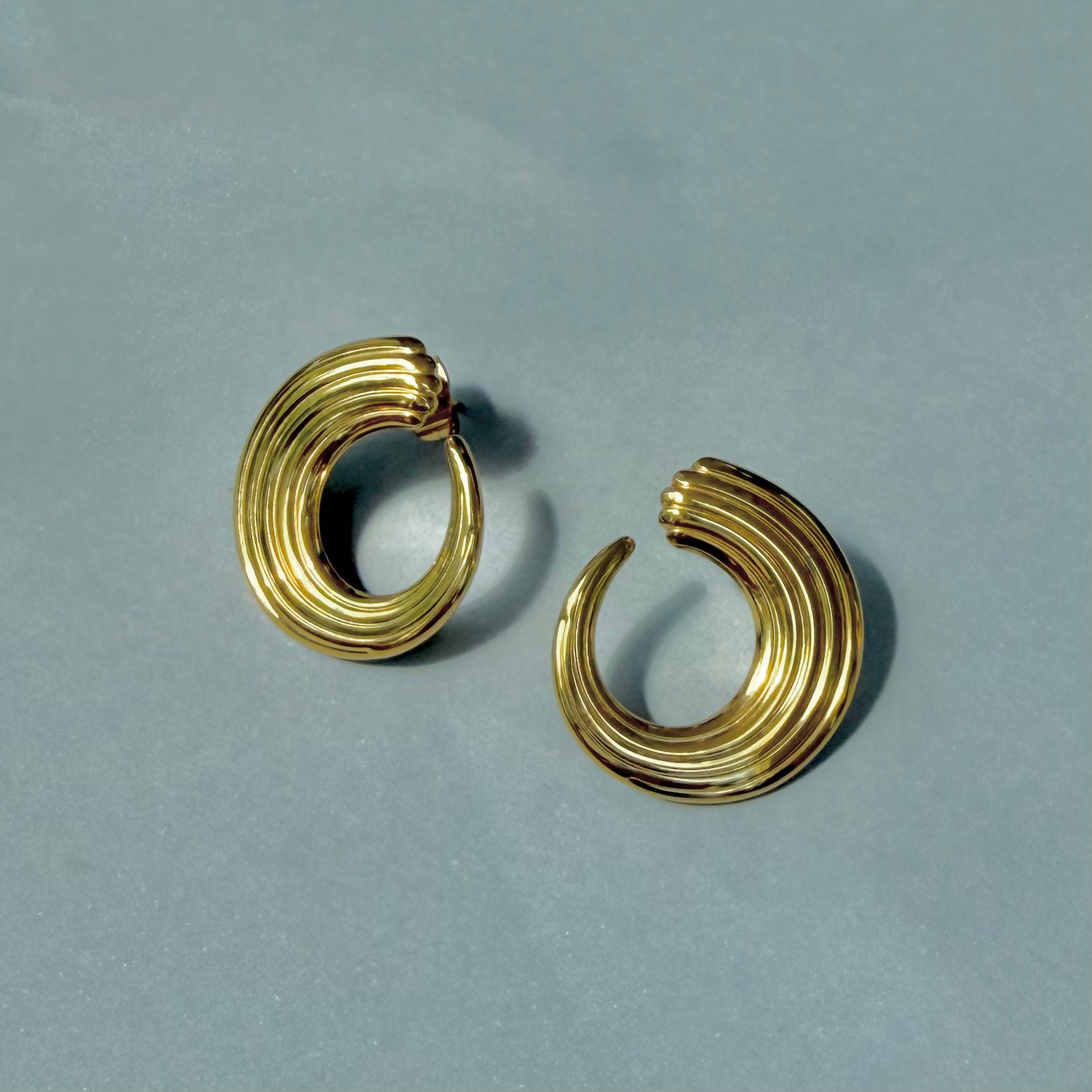 gold vintage inspired ribbed curve earrings on blue background