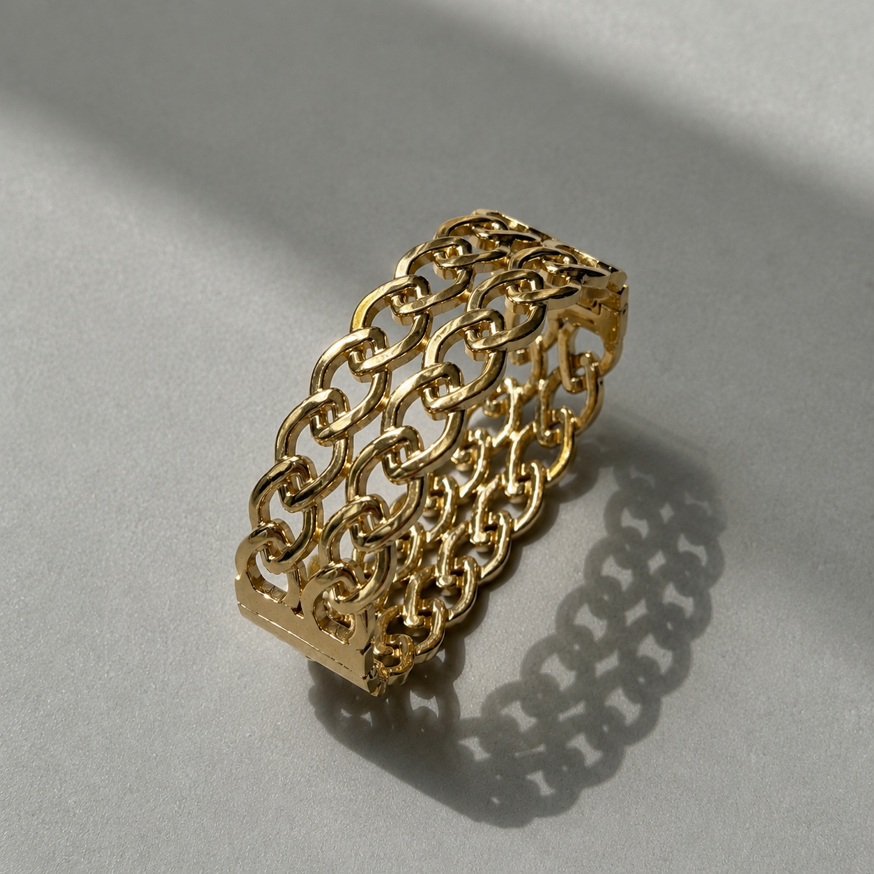 gold woven link cuff bracelet on grey background