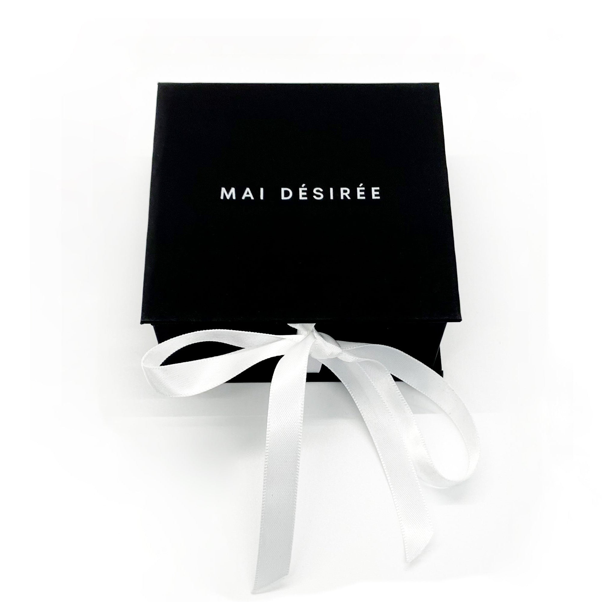 Black gift box with white ribbon and 'MAI DESIREE' branding on a white background