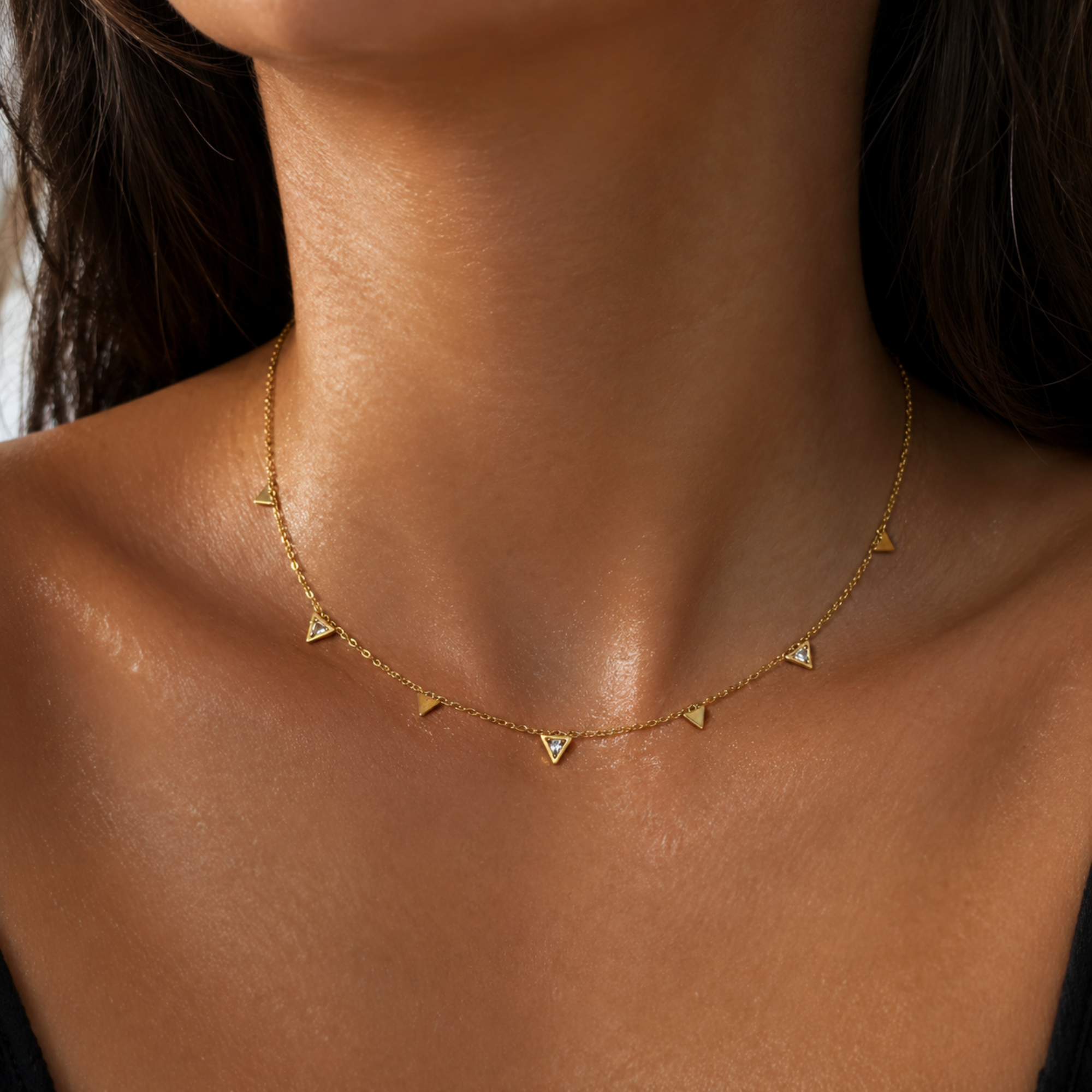 Gold necklace with small triangle pendants on a person's neck