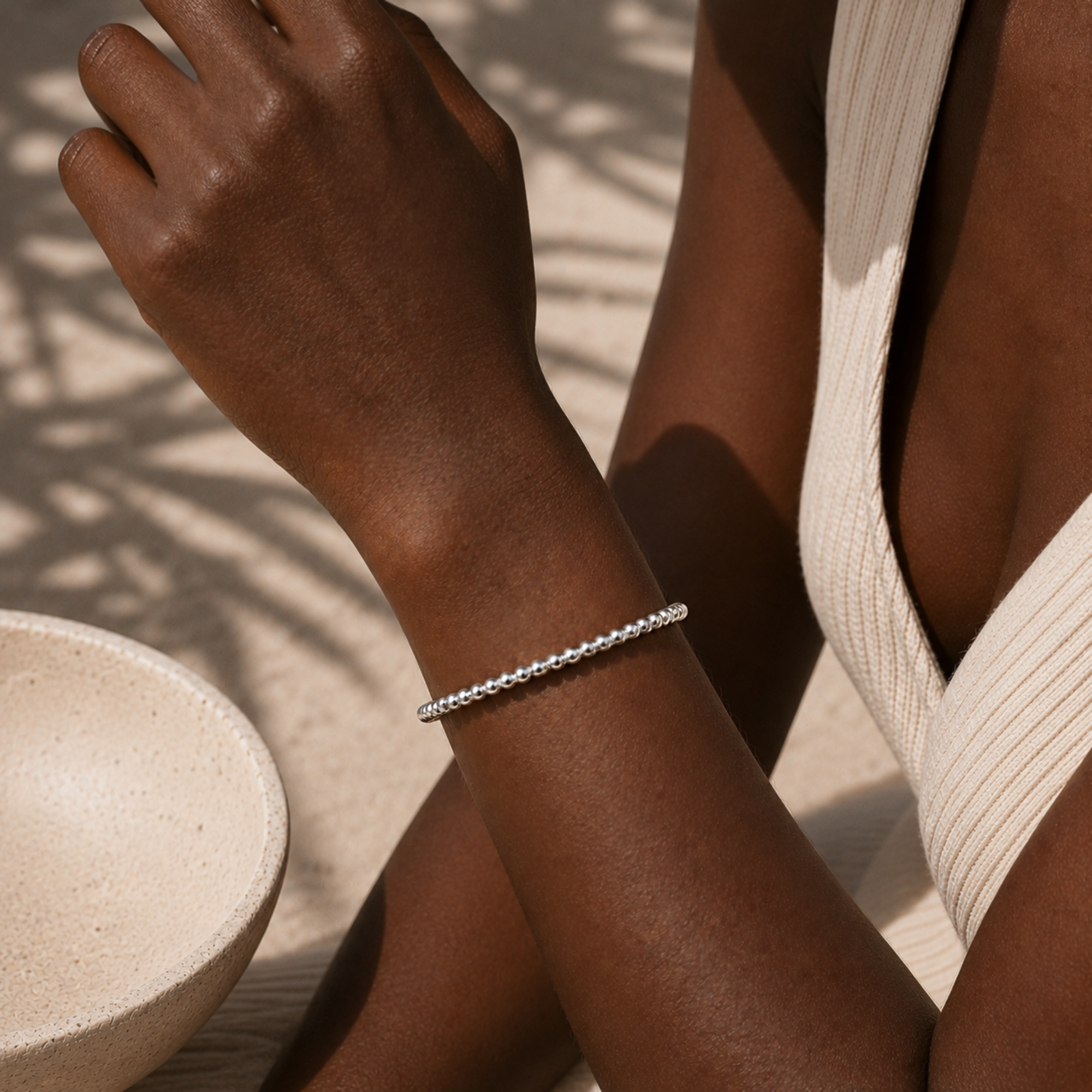 Close-up of a person's wrist wearing a silver beaded cuff bracelet with a neutral background.