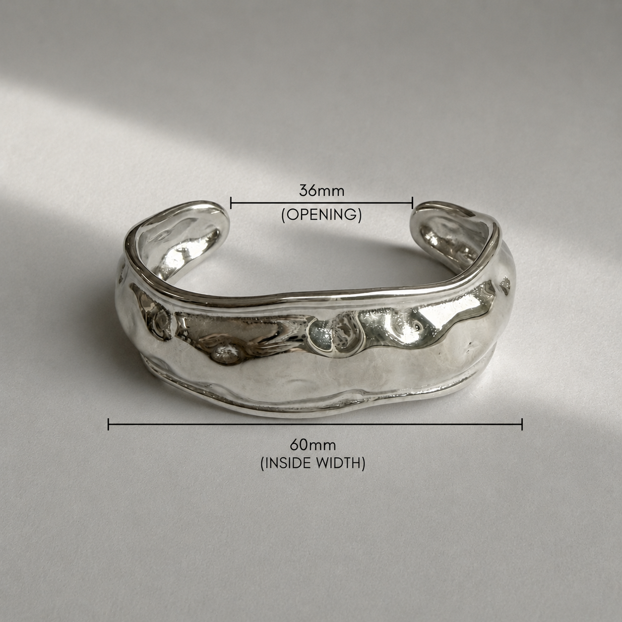 Silver bracelet with measurements on a gray background