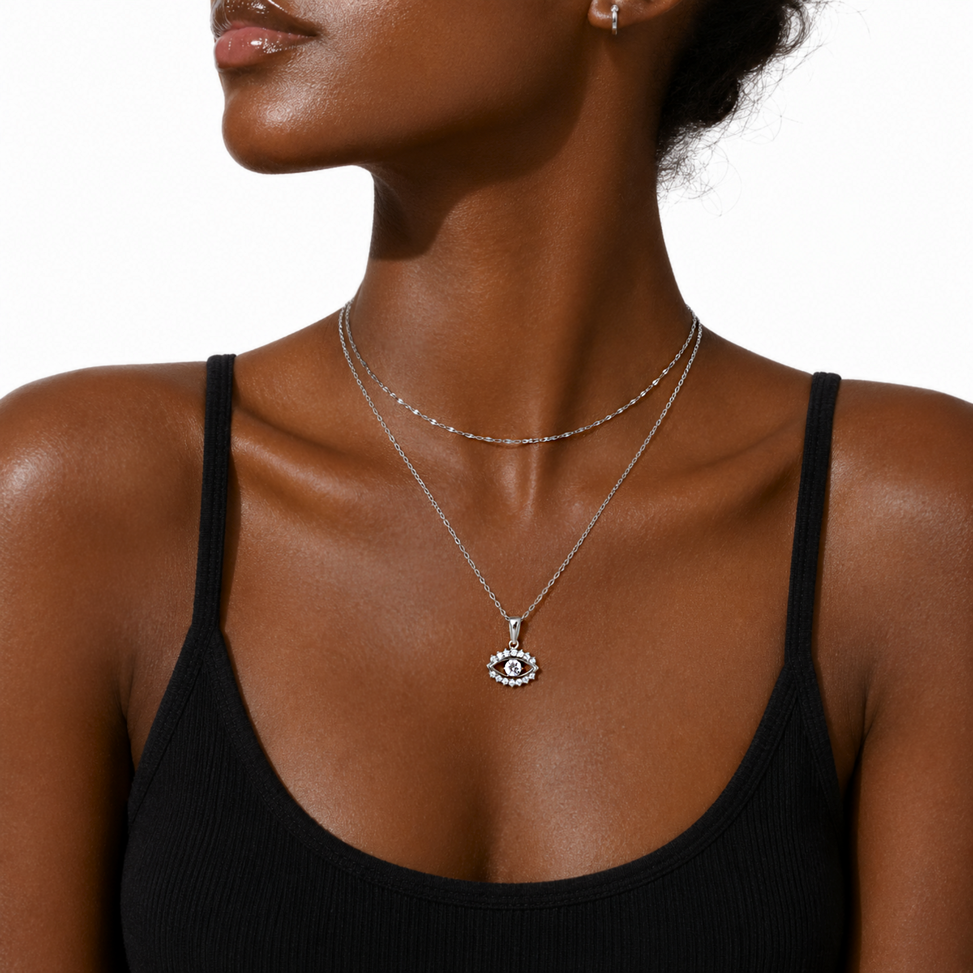 Woman wearing a dainty silver lace chain necklace with an silver diamond evil eye pendant on a white background
