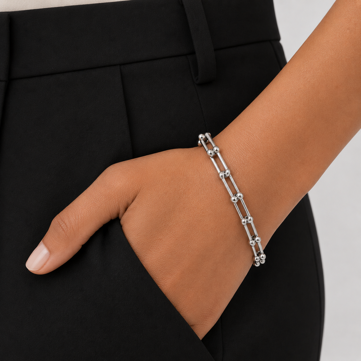 Silver bracelet on a person's wrist with a black suit background