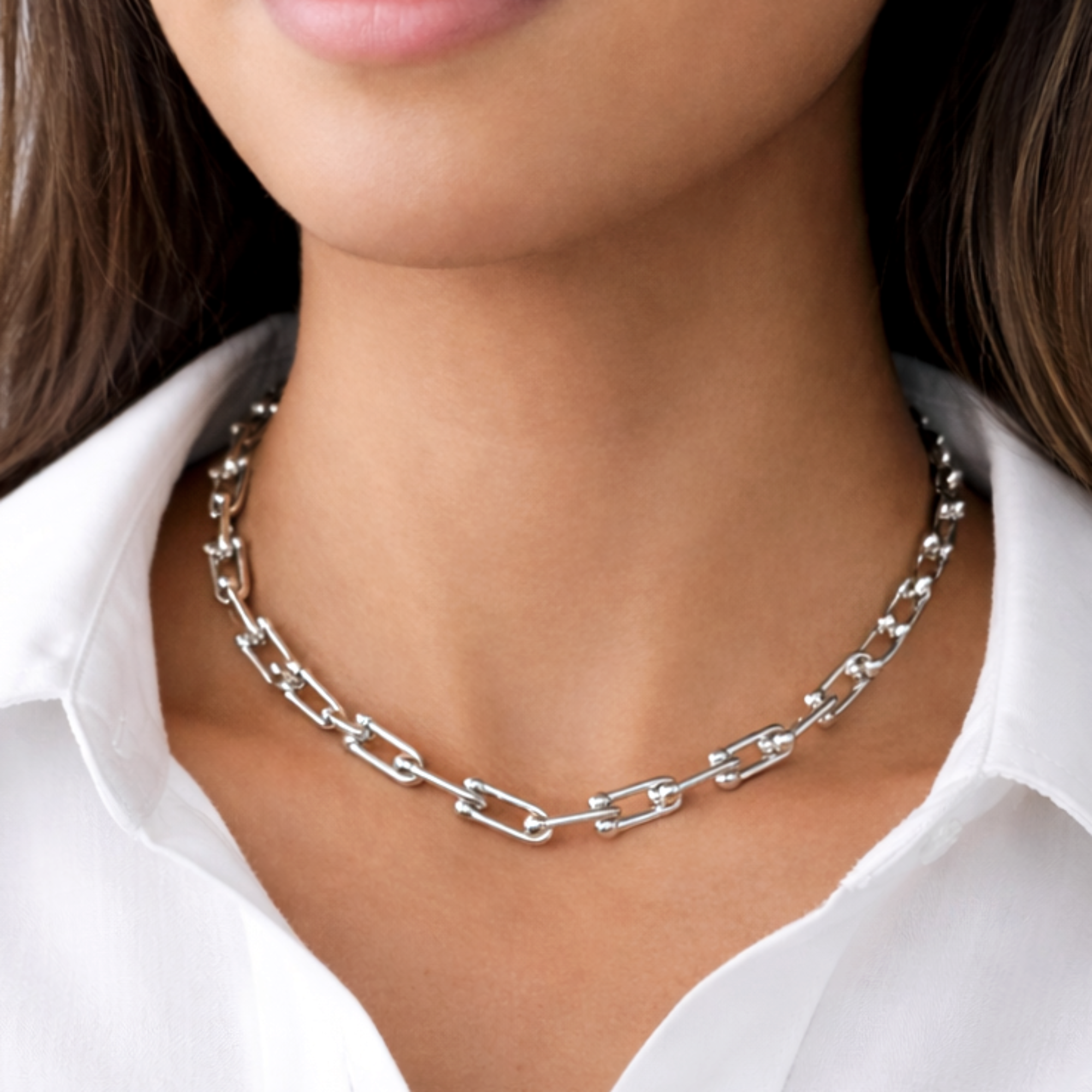 Silver chain necklace worn by a person with a white shirt