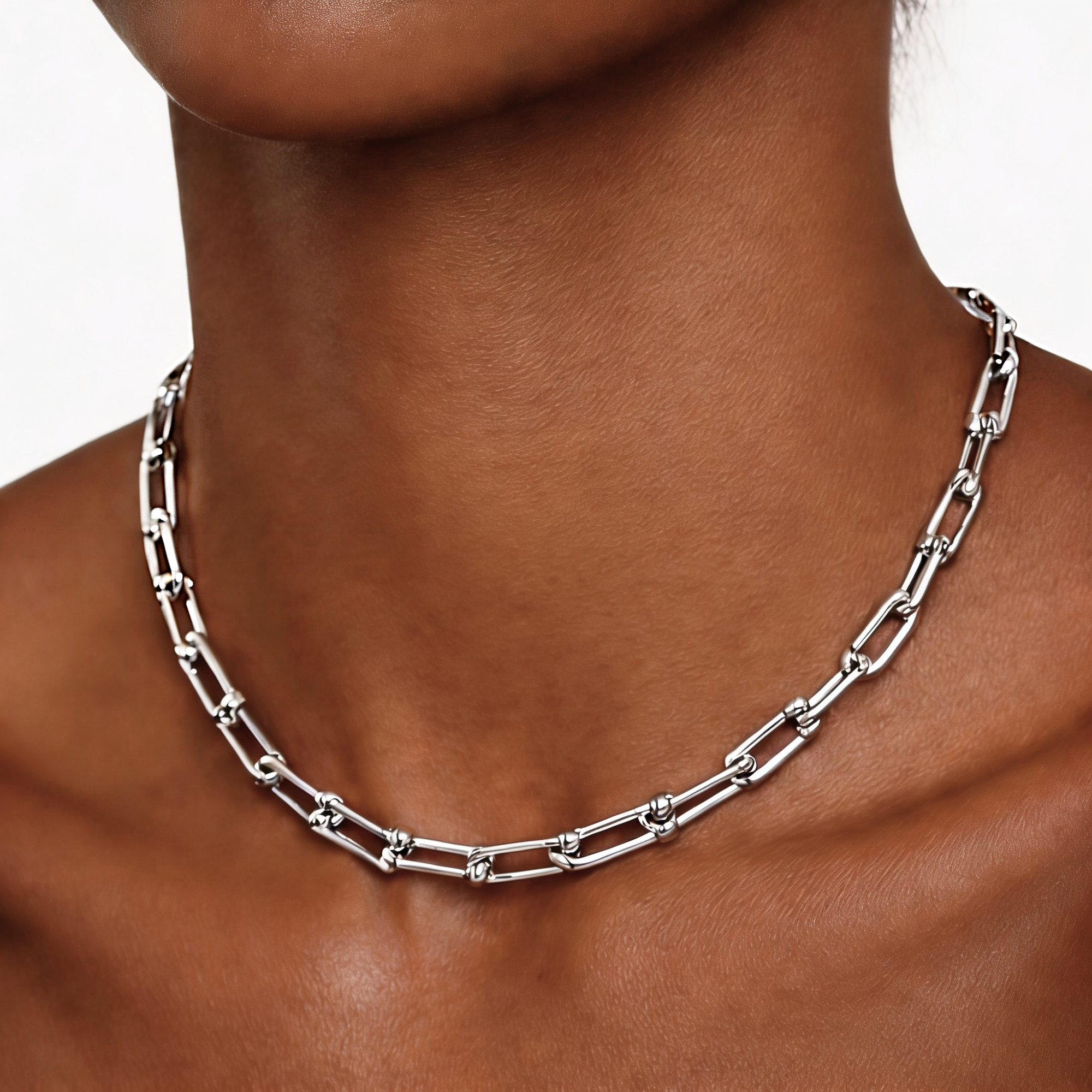 Silver chain necklace on a person's neck with a neutral background