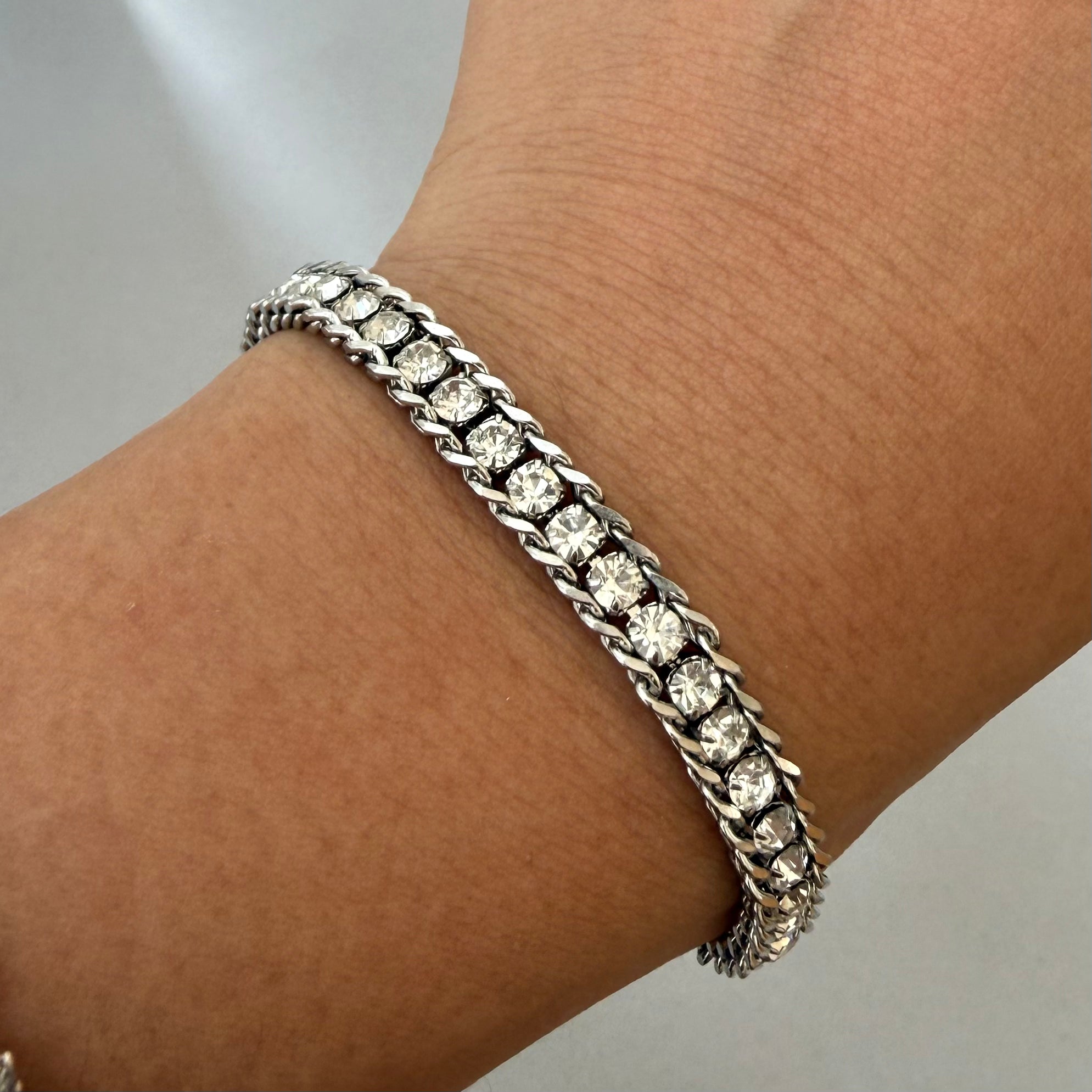 Silver bracelet with clear stones on a wrist against a neutral background