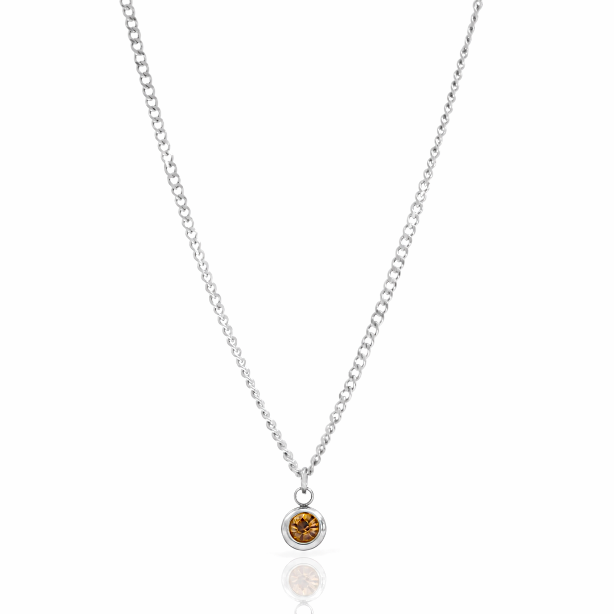 A delicate silver chain necklace with a small round bezel-set amber citrine gemstone pendant, displayed on a clean white background with a soft reflection below.